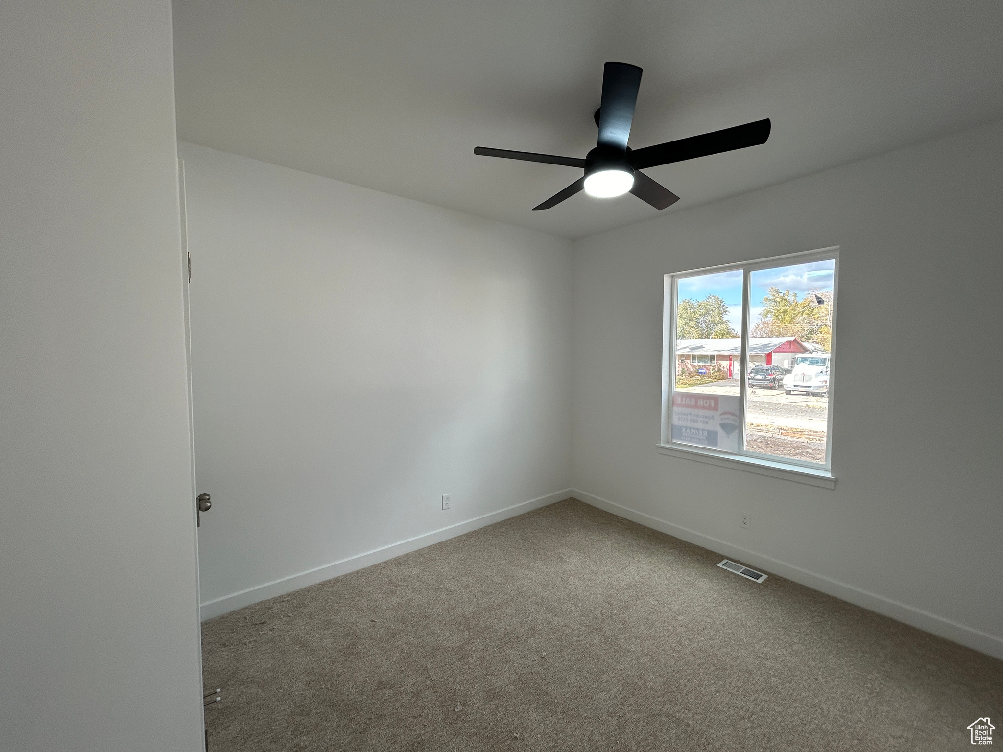 Empty room with ceiling fan and carpet floors