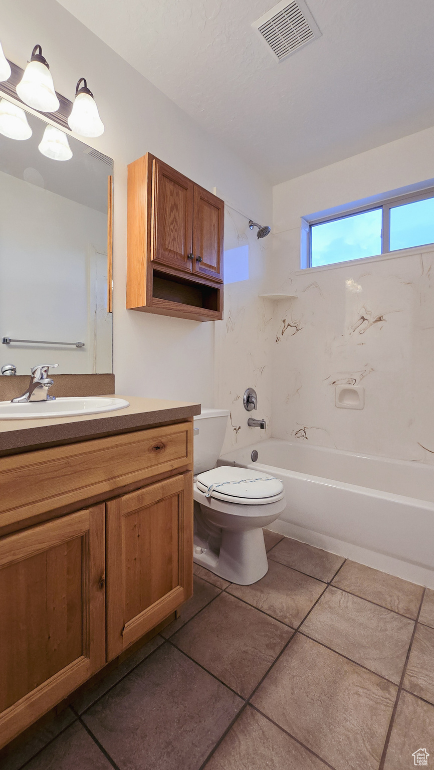 Full bathroom with toilet, vanity, tile patterned floors, and tiled shower / bath