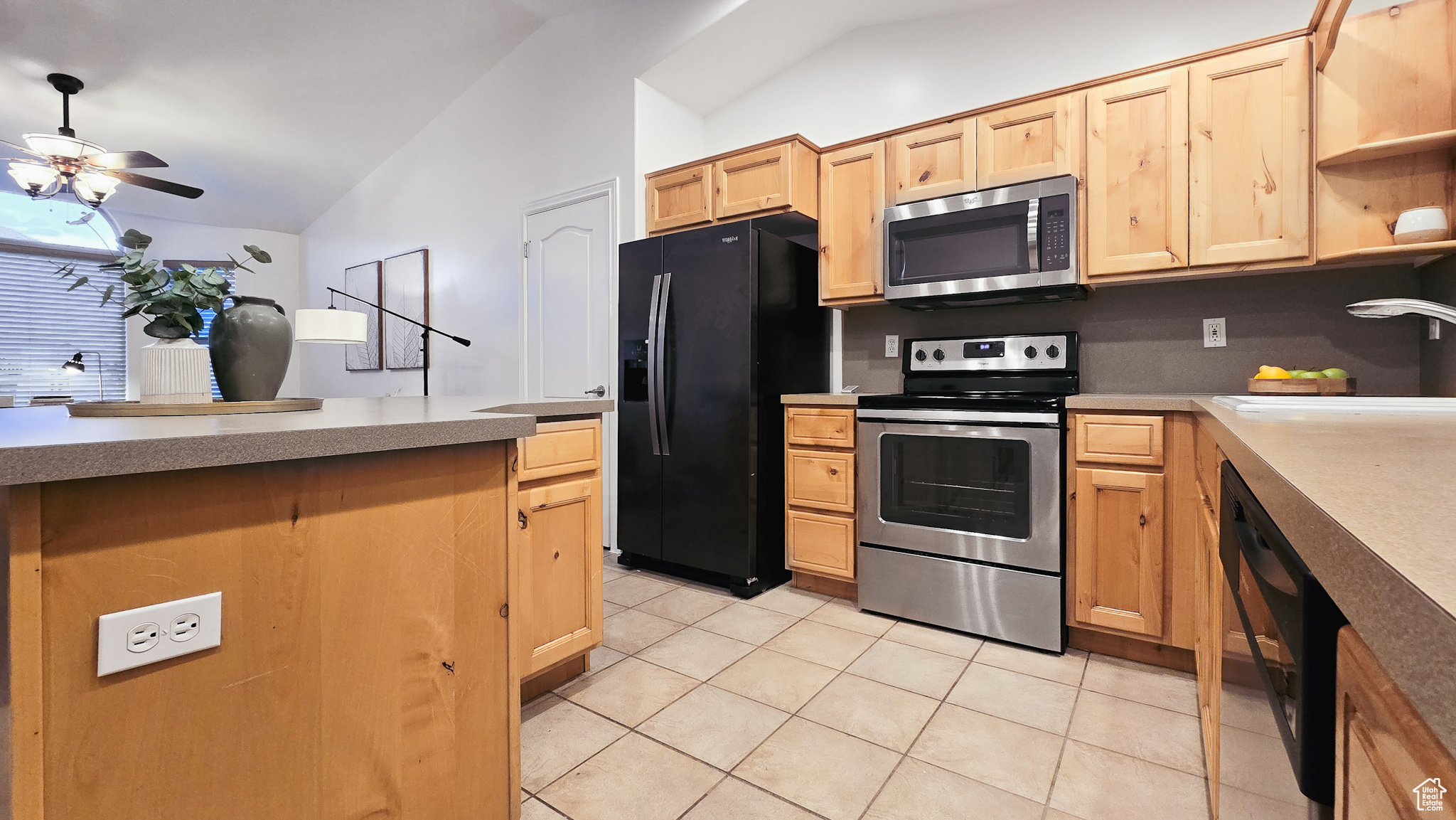 Kitchen featuring vaulted ceiling, ceiling fan, sink, black appliances, and light tile patterned flooring