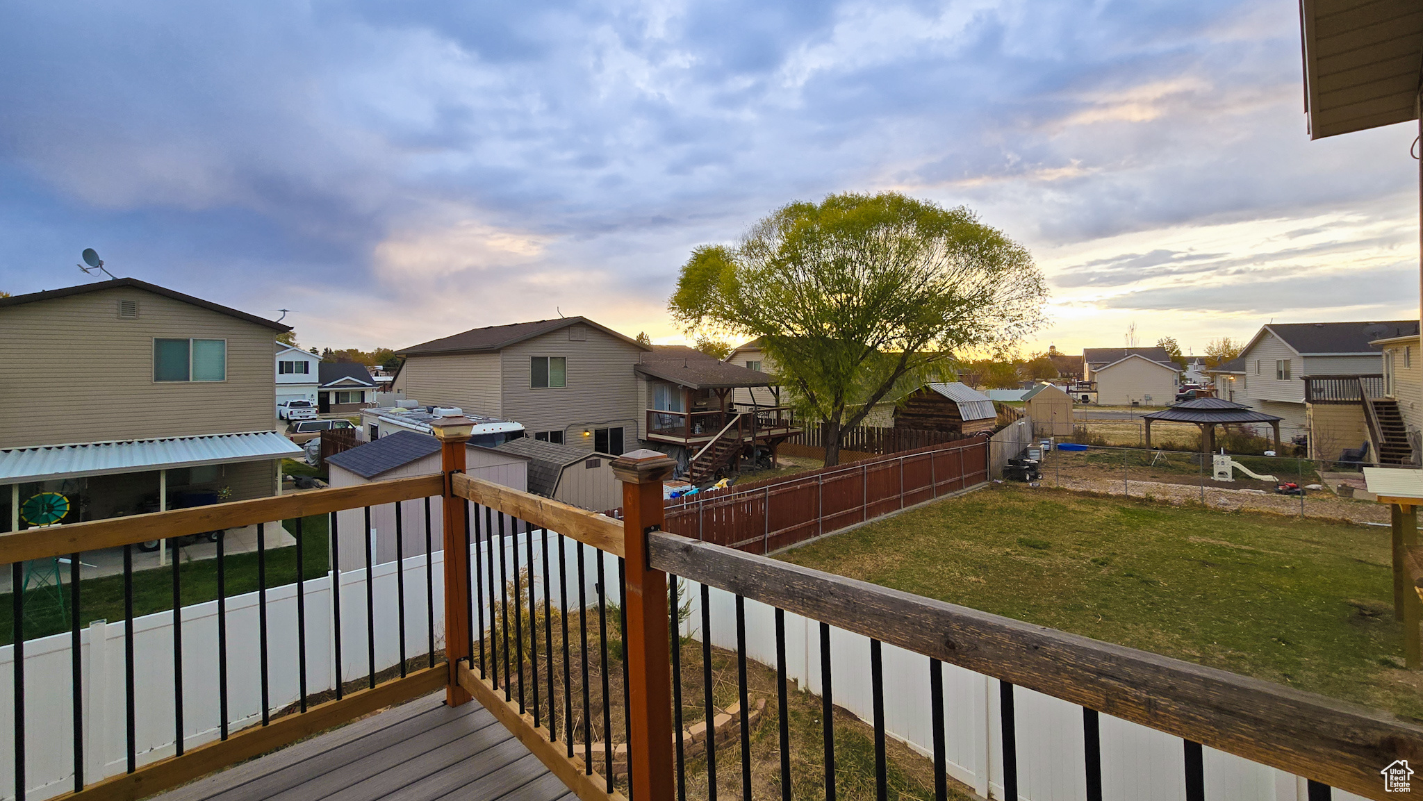 Deck at dusk with a gazebo and a yard