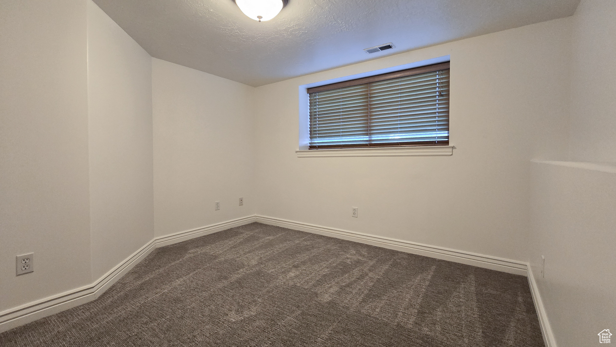 Carpeted spare room with a textured ceiling