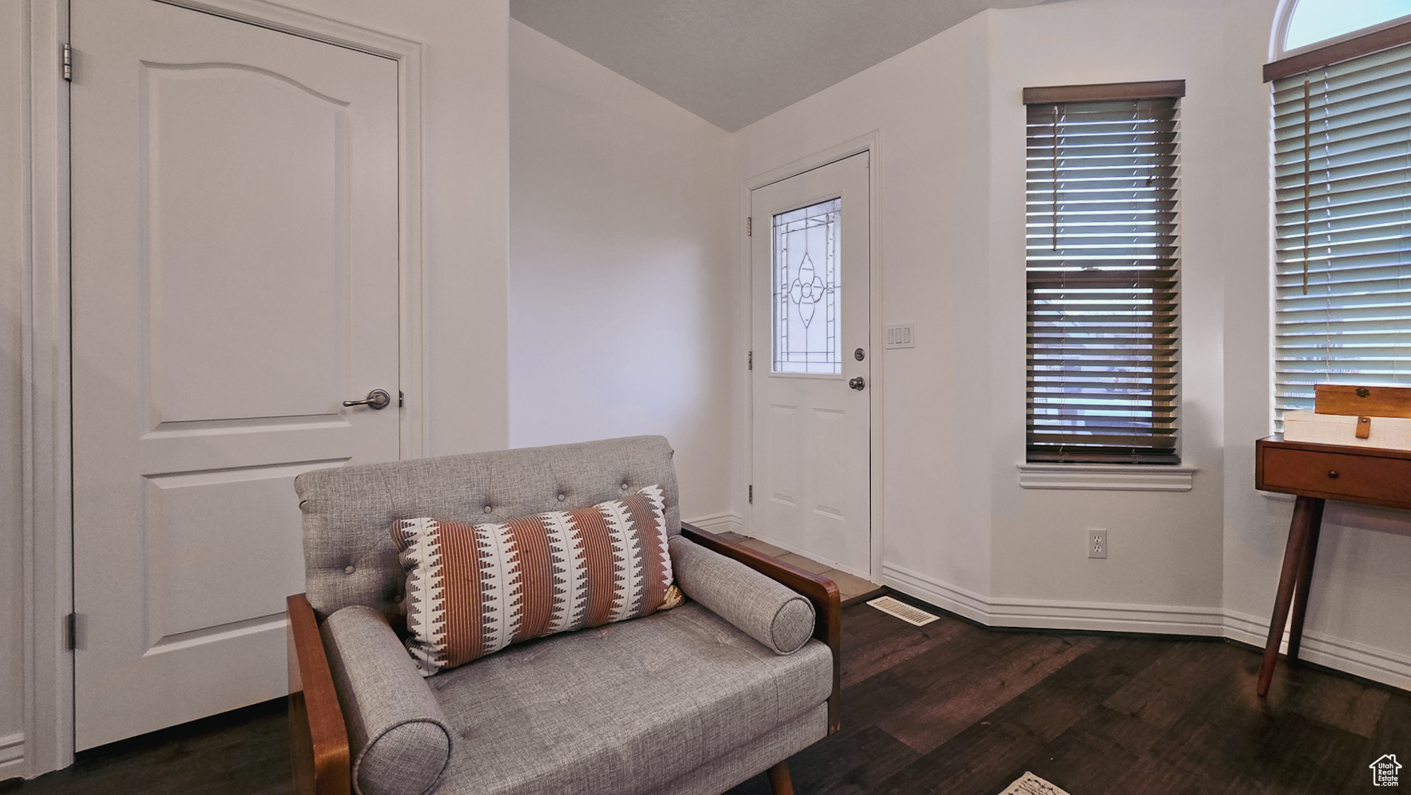 Sitting room with lofted ceiling and dark wood-type flooring