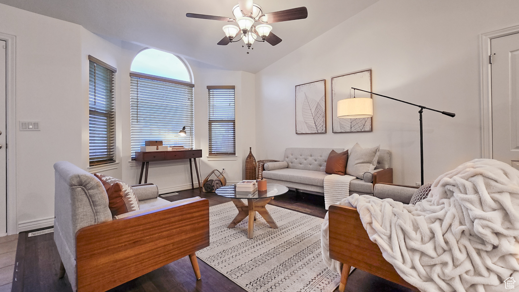 Living room featuring ceiling fan, lofted ceiling, and dark wood-type flooring