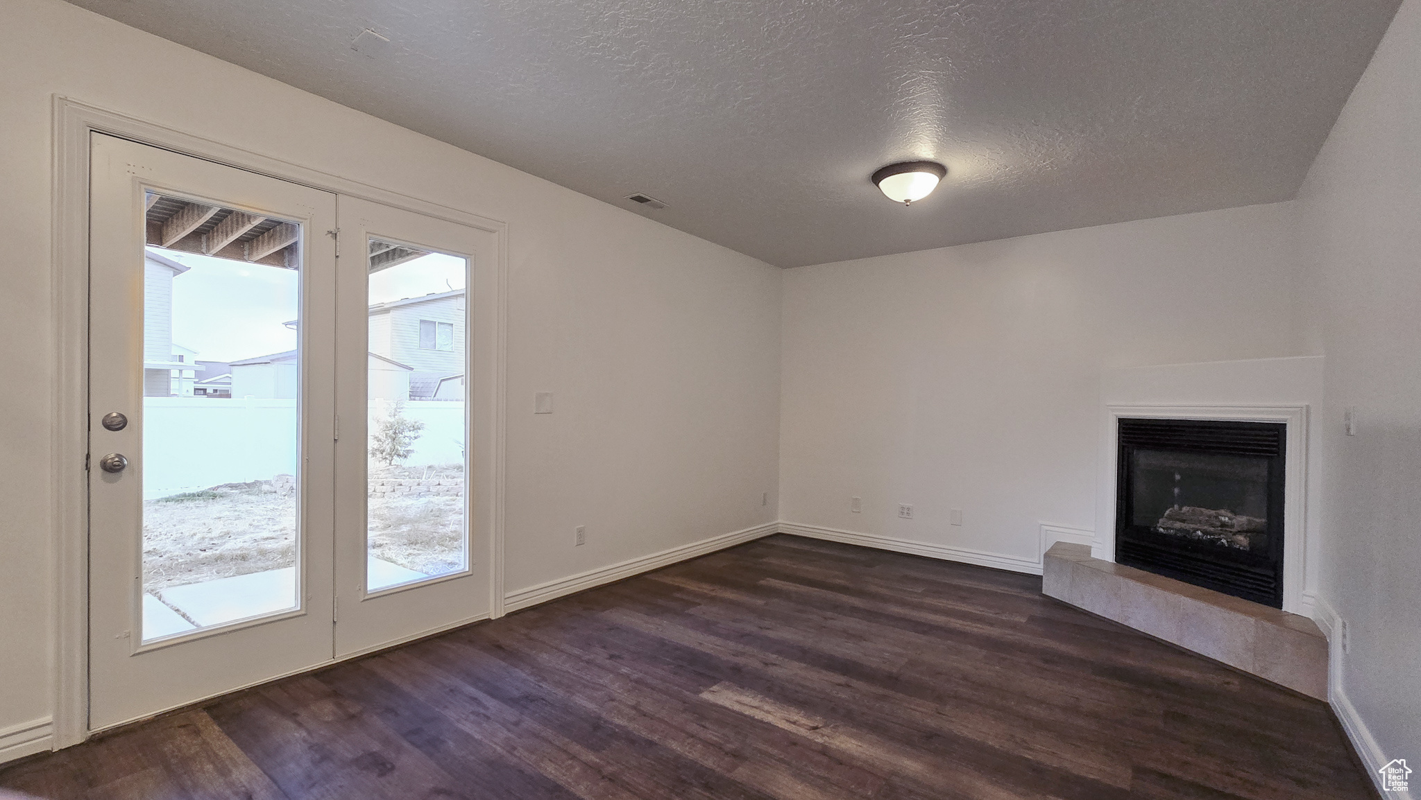 Unfurnished living room with plenty of natural light, dark hardwood / wood-style floors, and a textured ceiling