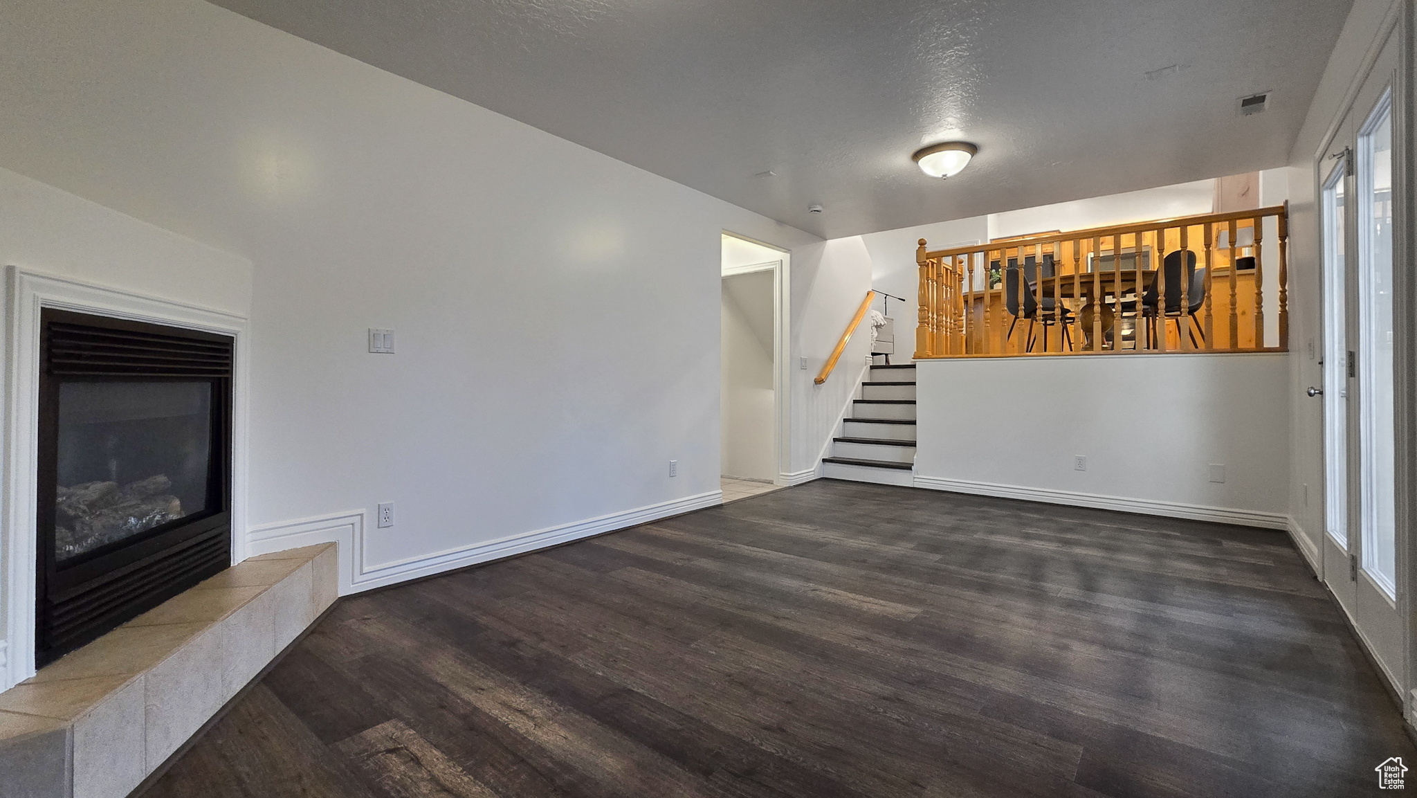 Unfurnished living room featuring a fireplace, dark wood-type flooring, and a textured ceiling