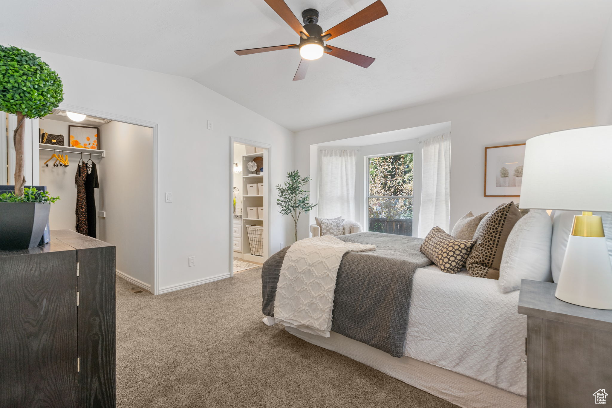 Carpeted bedroom with ceiling fan, a closet, lofted ceiling, and ensuite bath