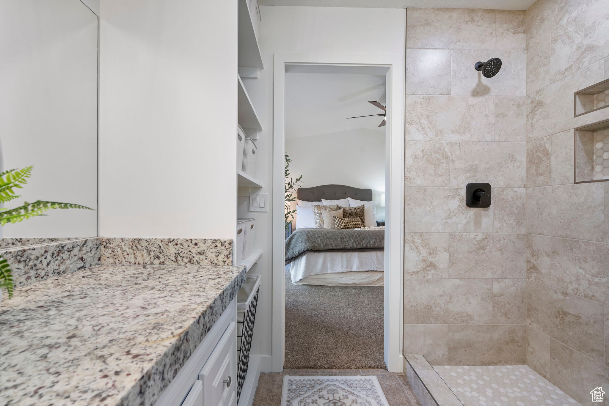 Bathroom with a tile shower, ceiling fan, and vanity