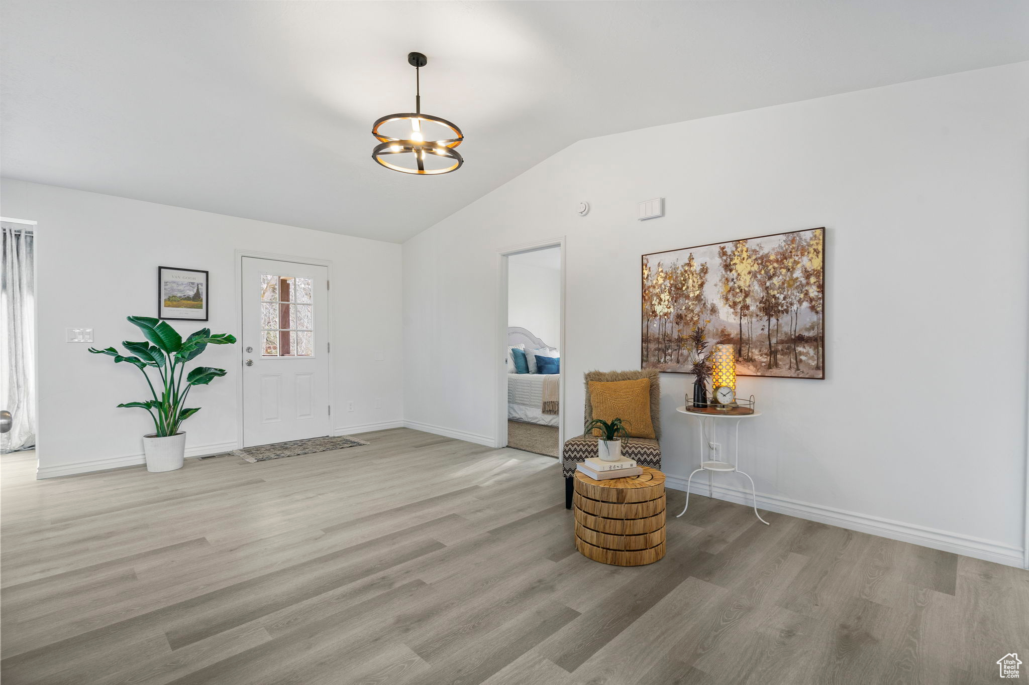 Unfurnished room with a chandelier, light hardwood / wood-style floors, and vaulted ceiling