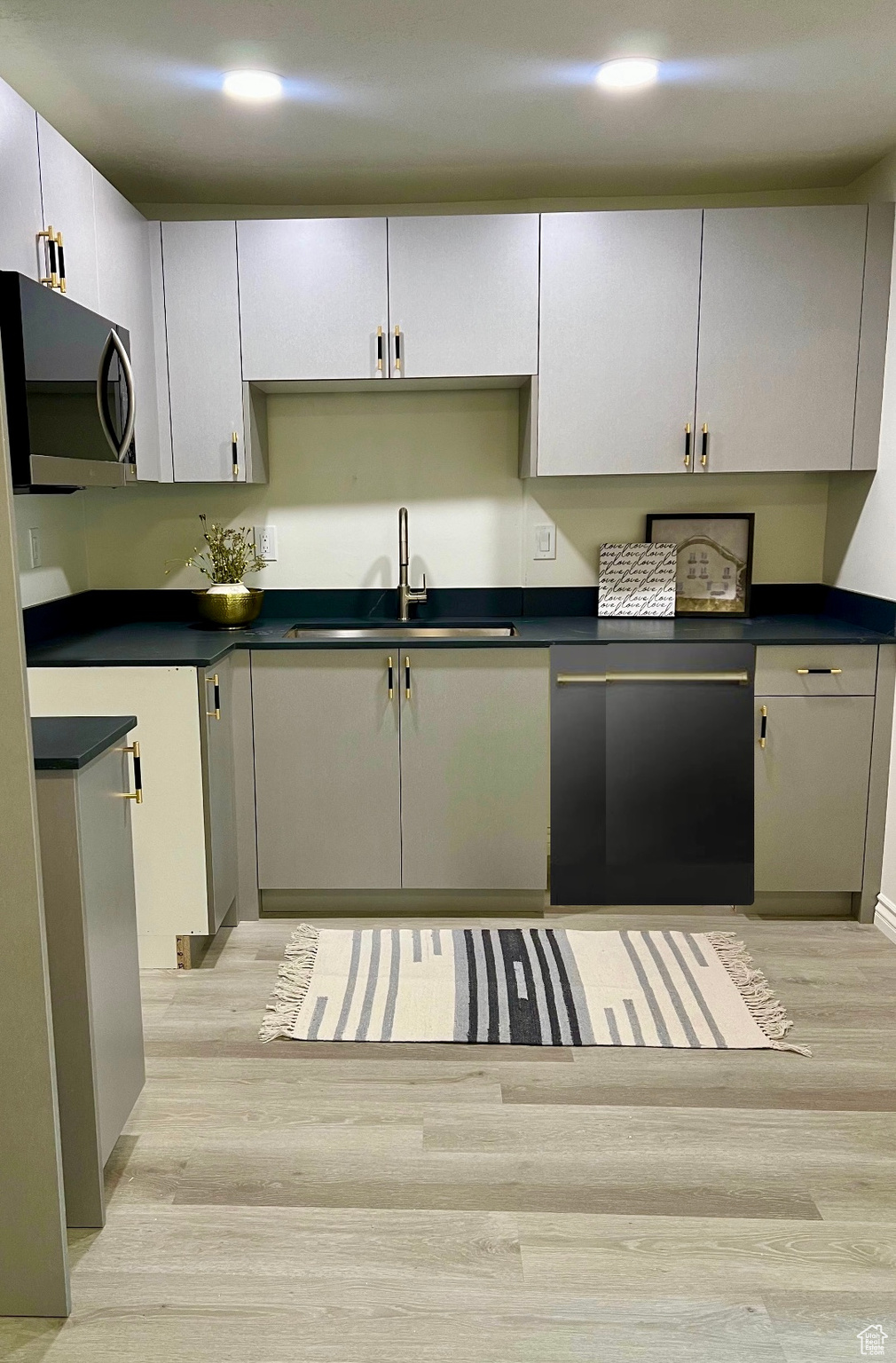 Kitchen featuring gray cabinets, sink, light hardwood / wood-style floors, and black dishwasher