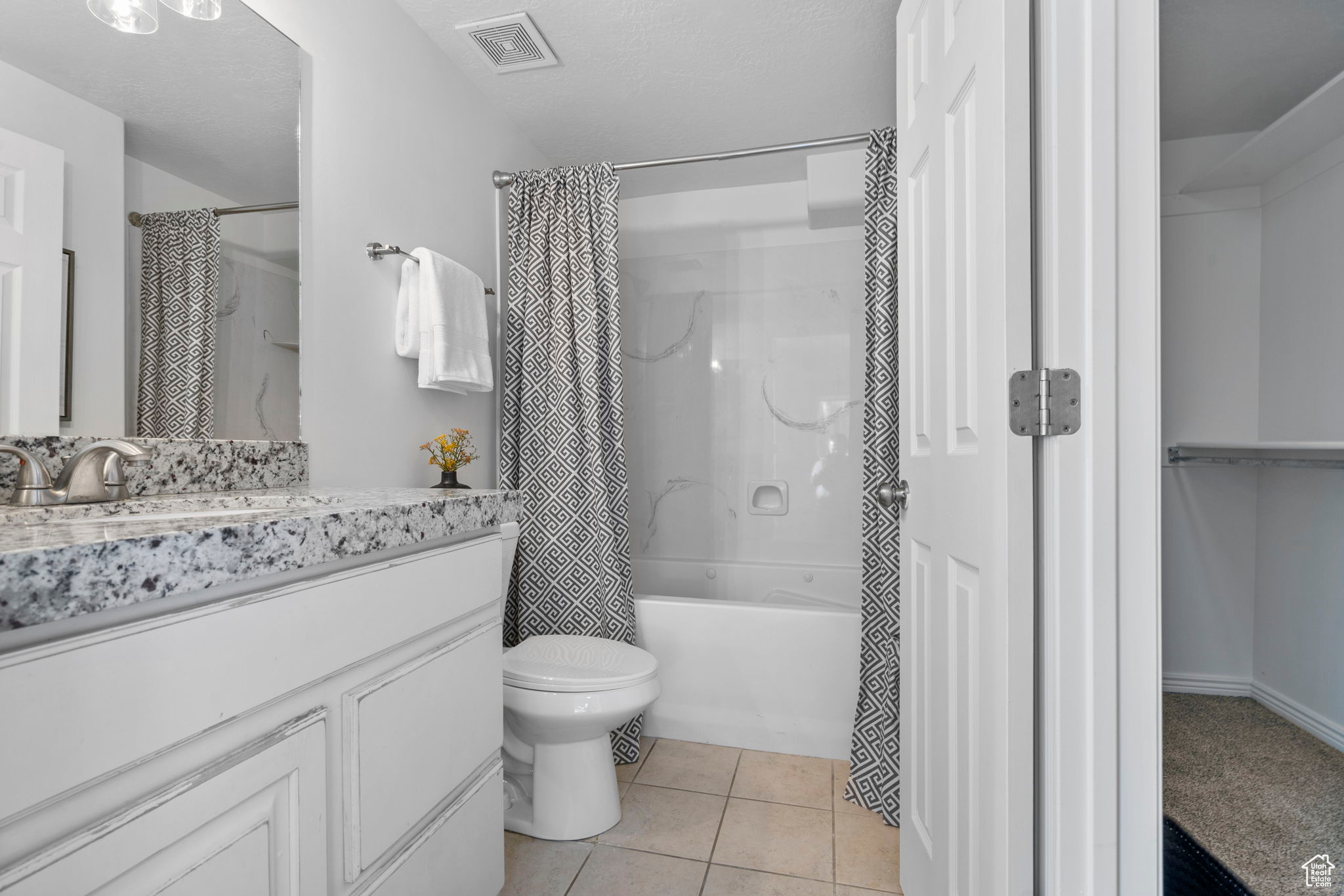 Full bathroom featuring vanity, tile patterned floors, toilet, shower / bathtub combination with curtain, and a textured ceiling