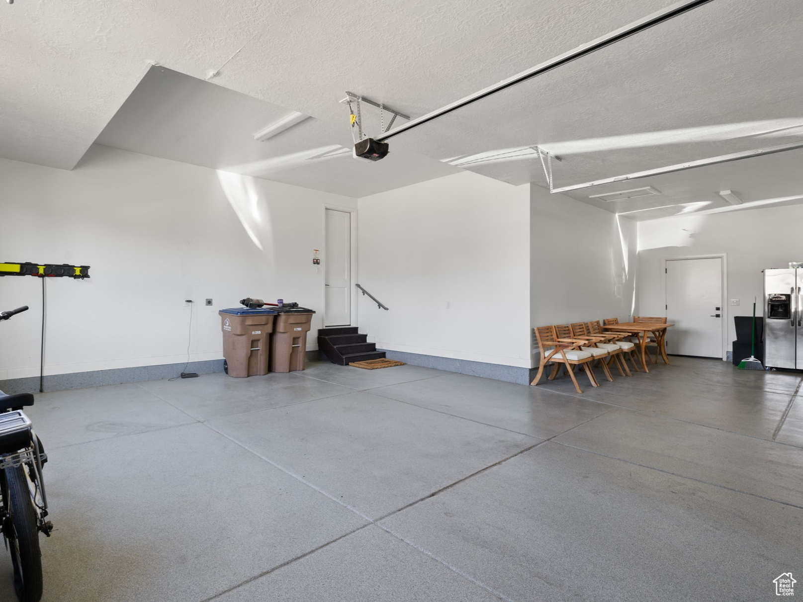 Garage featuring stainless steel refrigerator with ice dispenser and a garage door opener