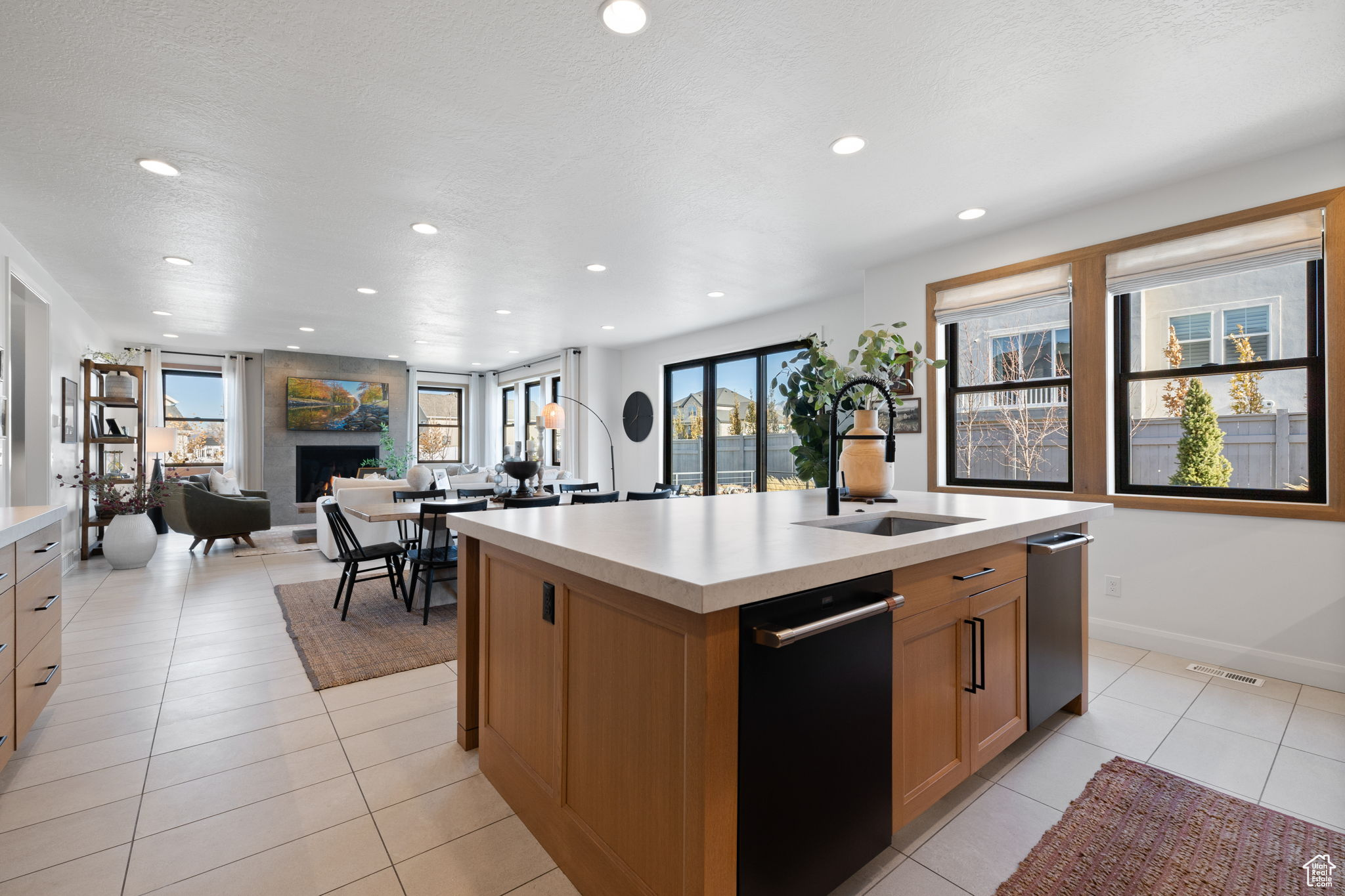 Kitchen with light tile patterned floors, a large fireplace, a kitchen island with sink, and sink