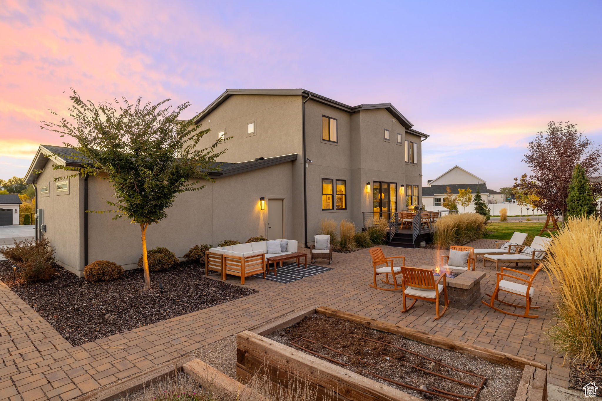 Back house at dusk featuring an outdoor living space with a fire pit and a patio area