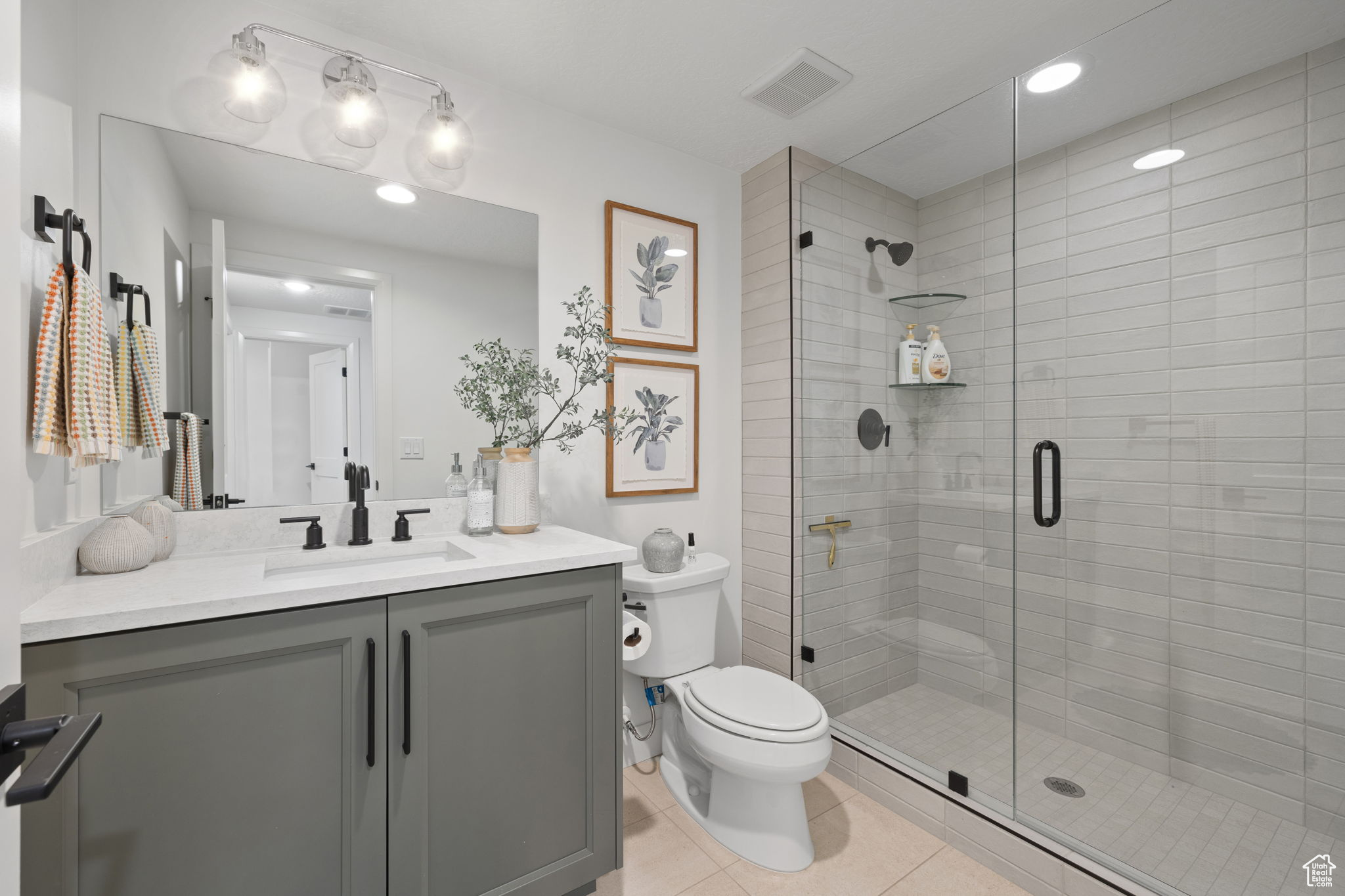 Bathroom with tile patterned floors, vanity, a shower with shower door, and toilet