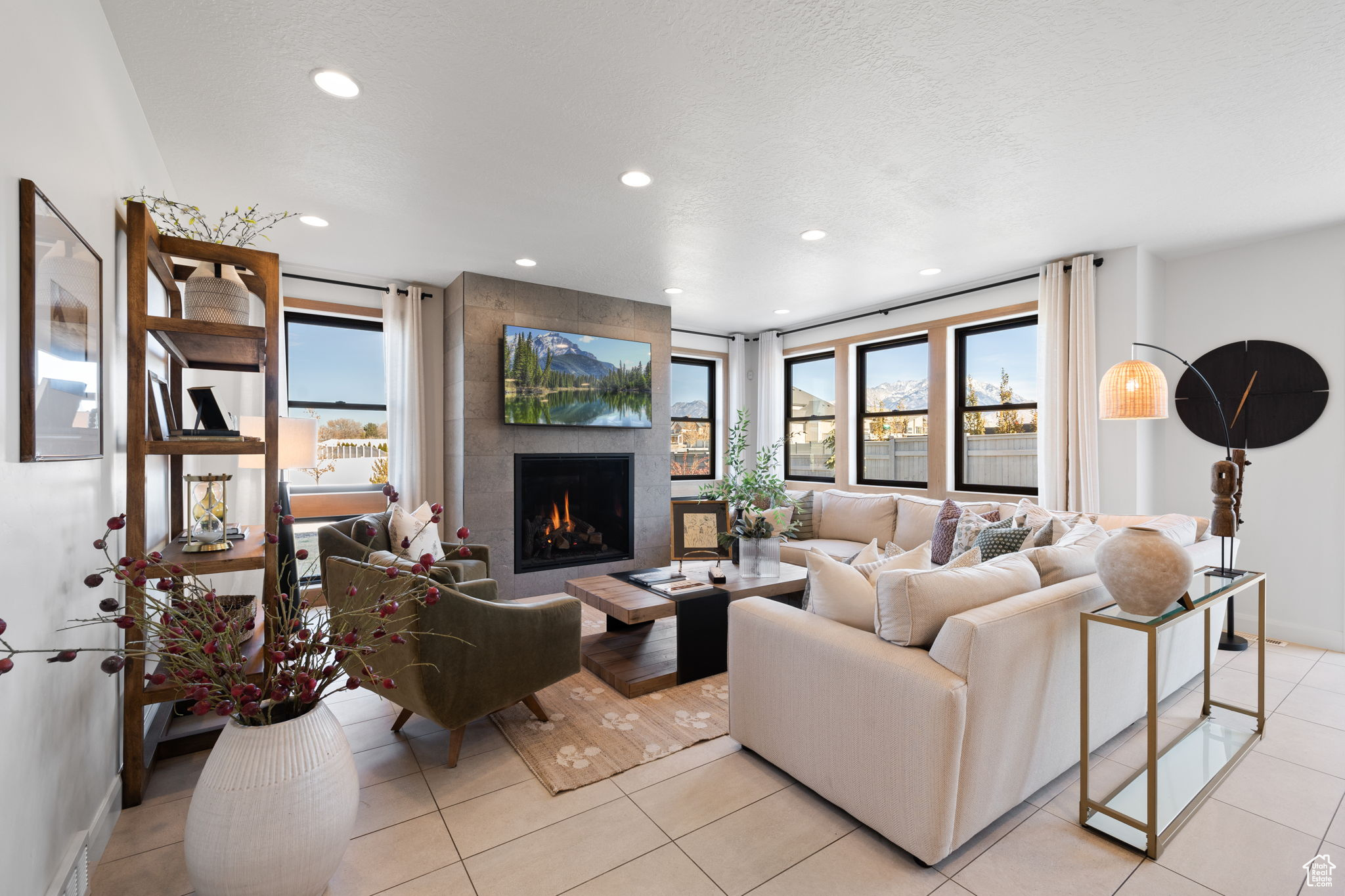 Living room featuring a fireplace, a textured ceiling, plenty of natural light, and light tile patterned flooring