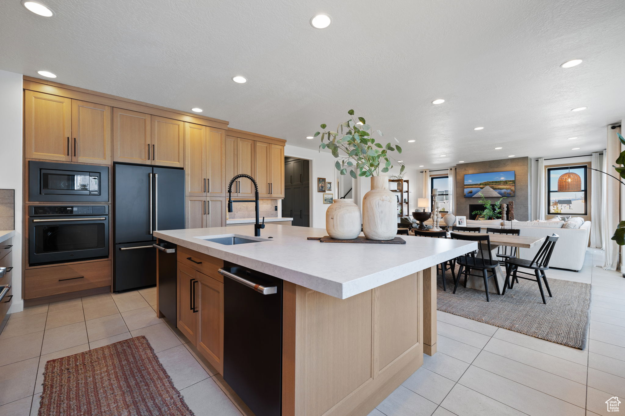 Kitchen with light tile patterned flooring, sink, stainless steel appliances, and a kitchen island with sink