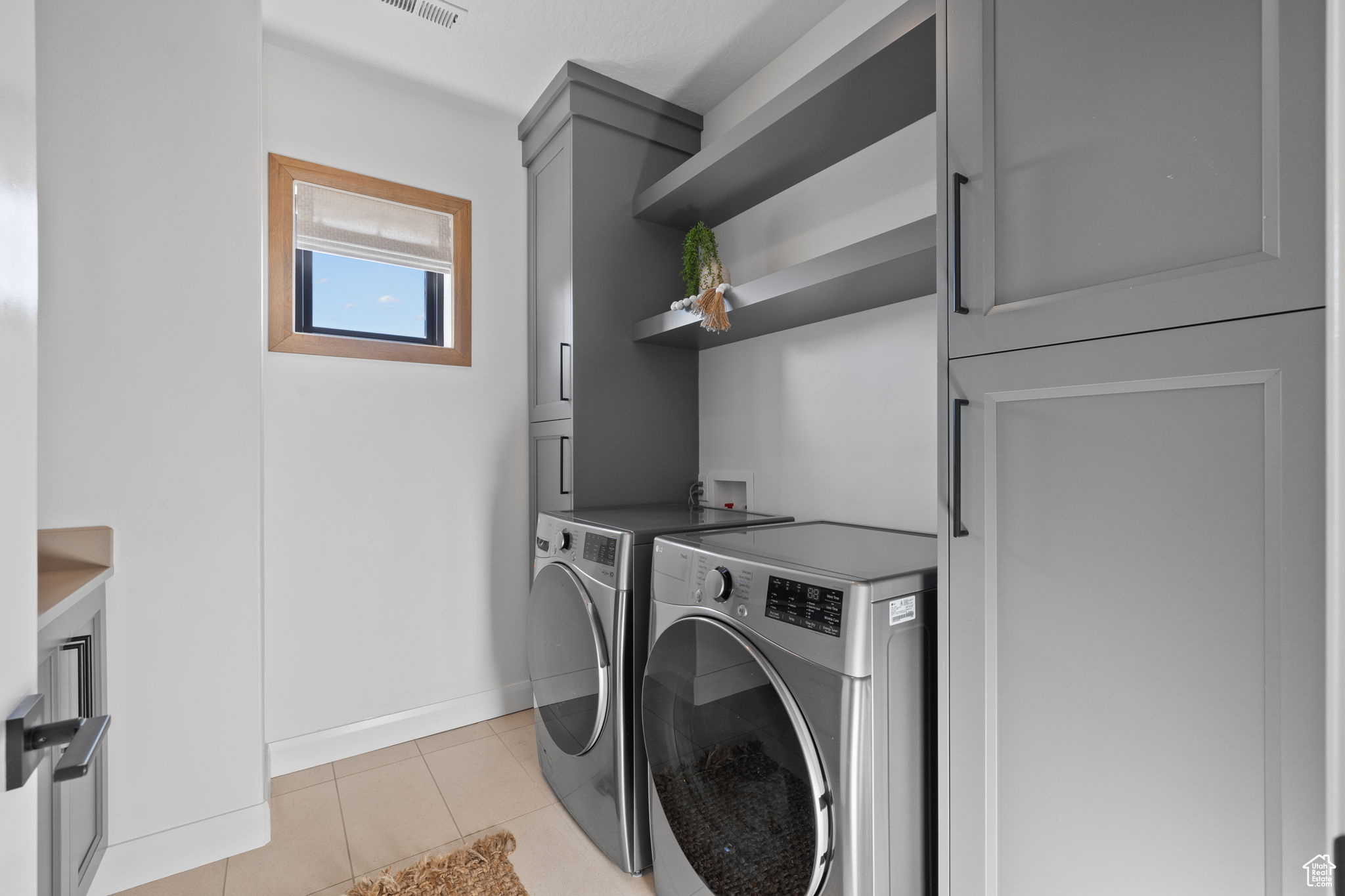 Washroom featuring washer and clothes dryer, light tile patterned flooring, and cabinets