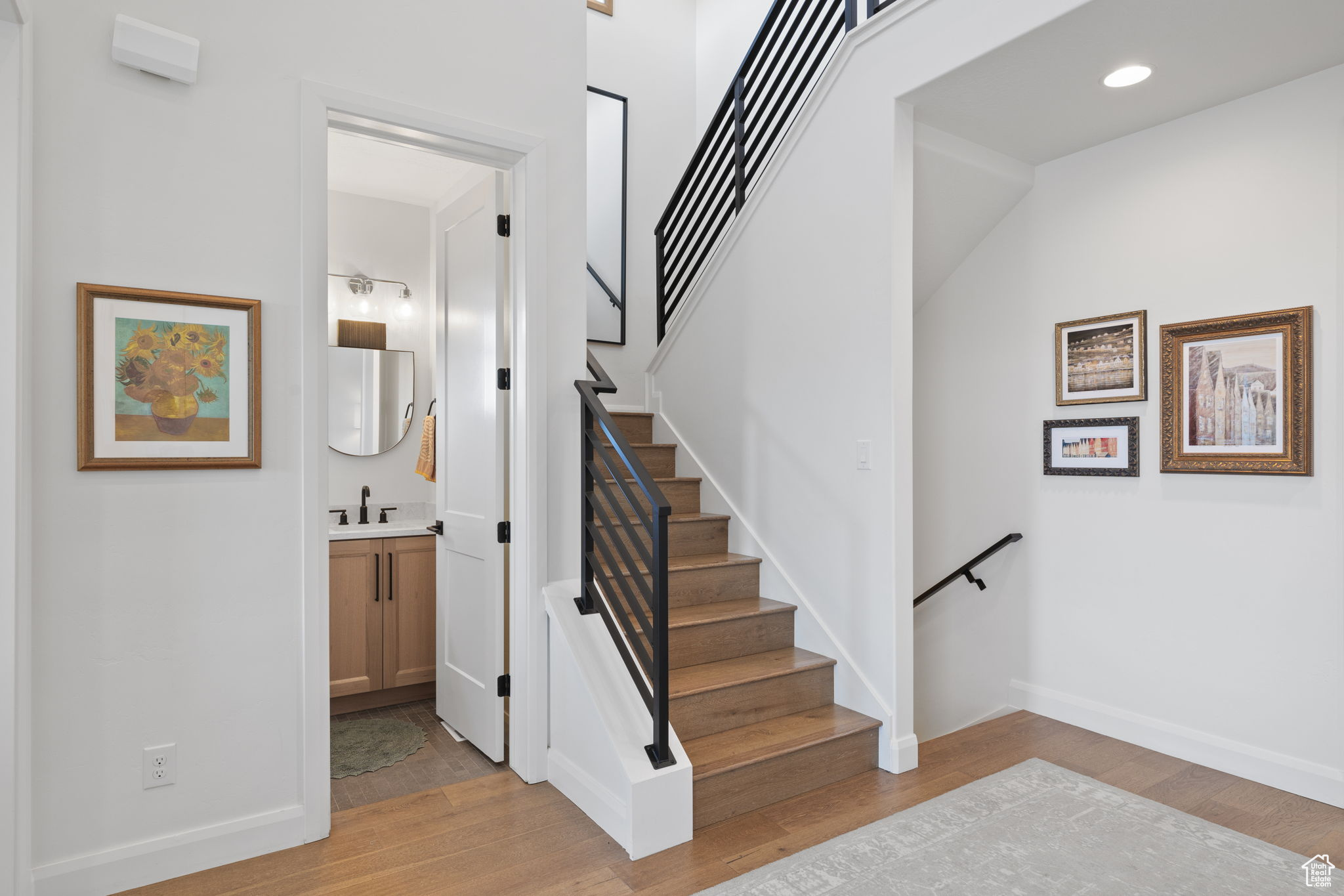 Stairs with hardwood / wood-style floors, vaulted ceiling, and sink