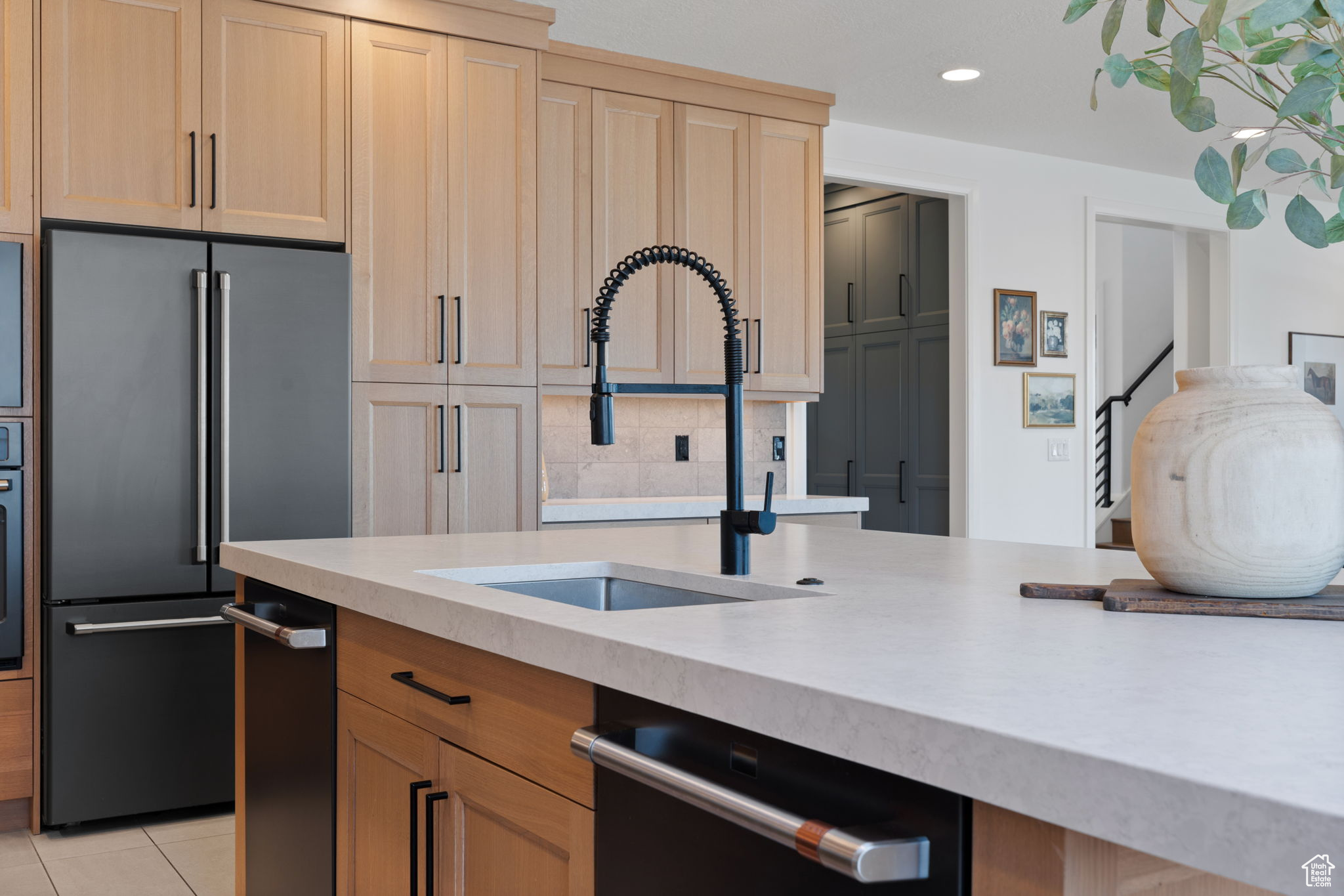 Kitchen with light tile patterned flooring, light brown cabinetry, sink, and appliances with stainless steel finishes