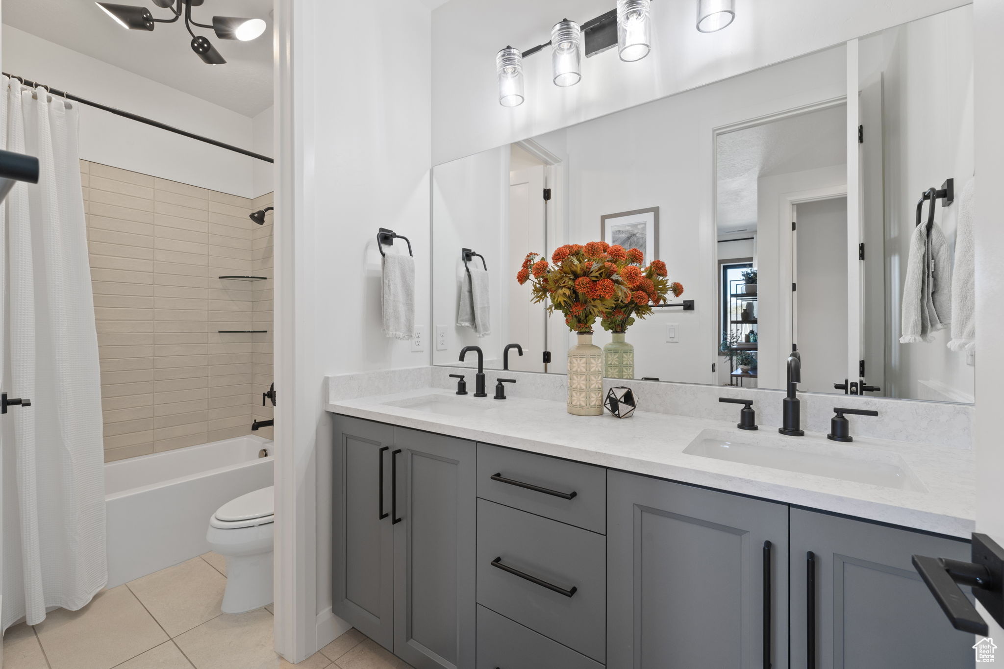 Full bathroom with tile patterned floors, vanity, toilet, and shower / bath combo with shower curtain