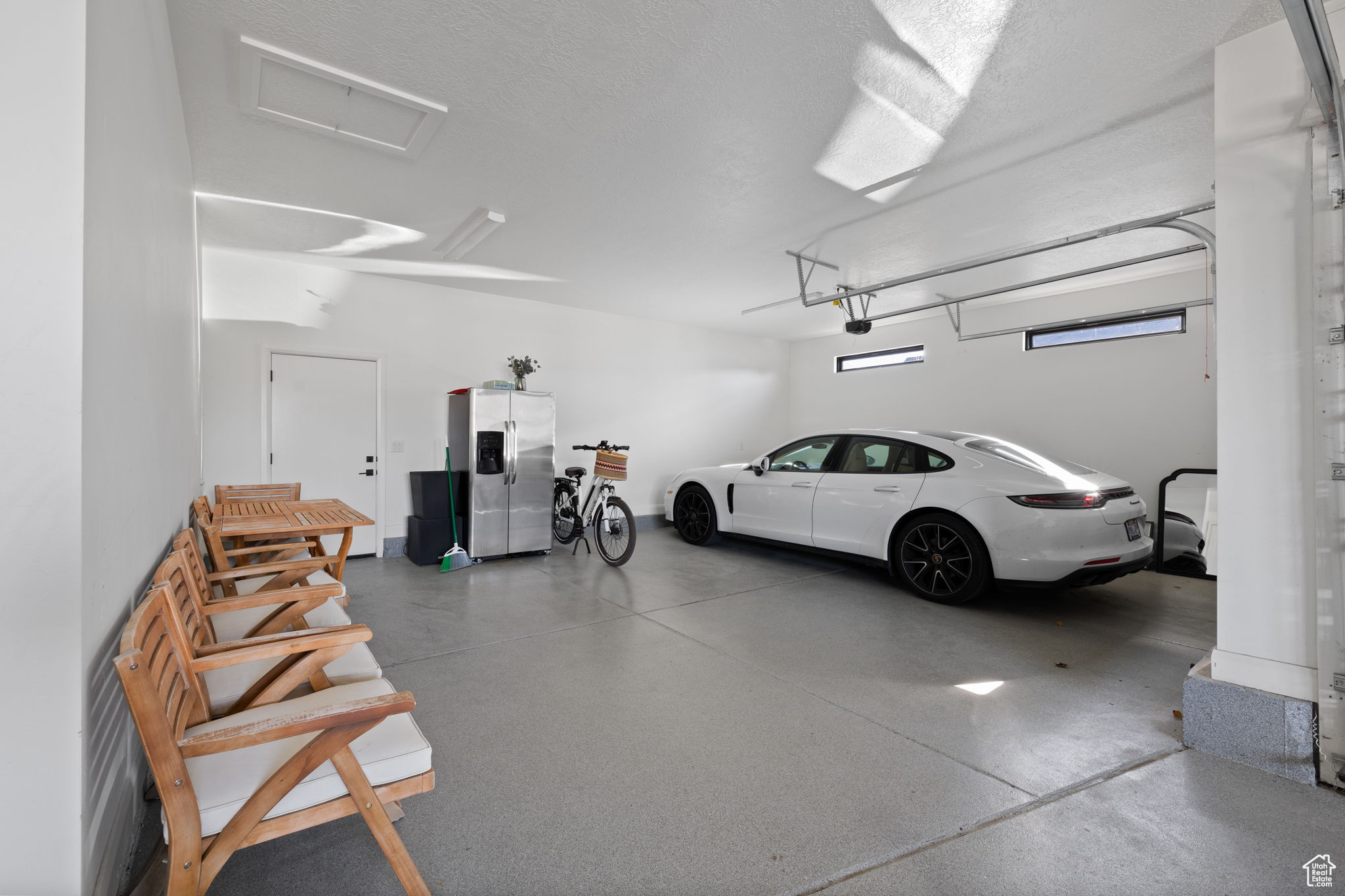 Garage featuring stainless steel fridge with ice dispenser and a garage door opener