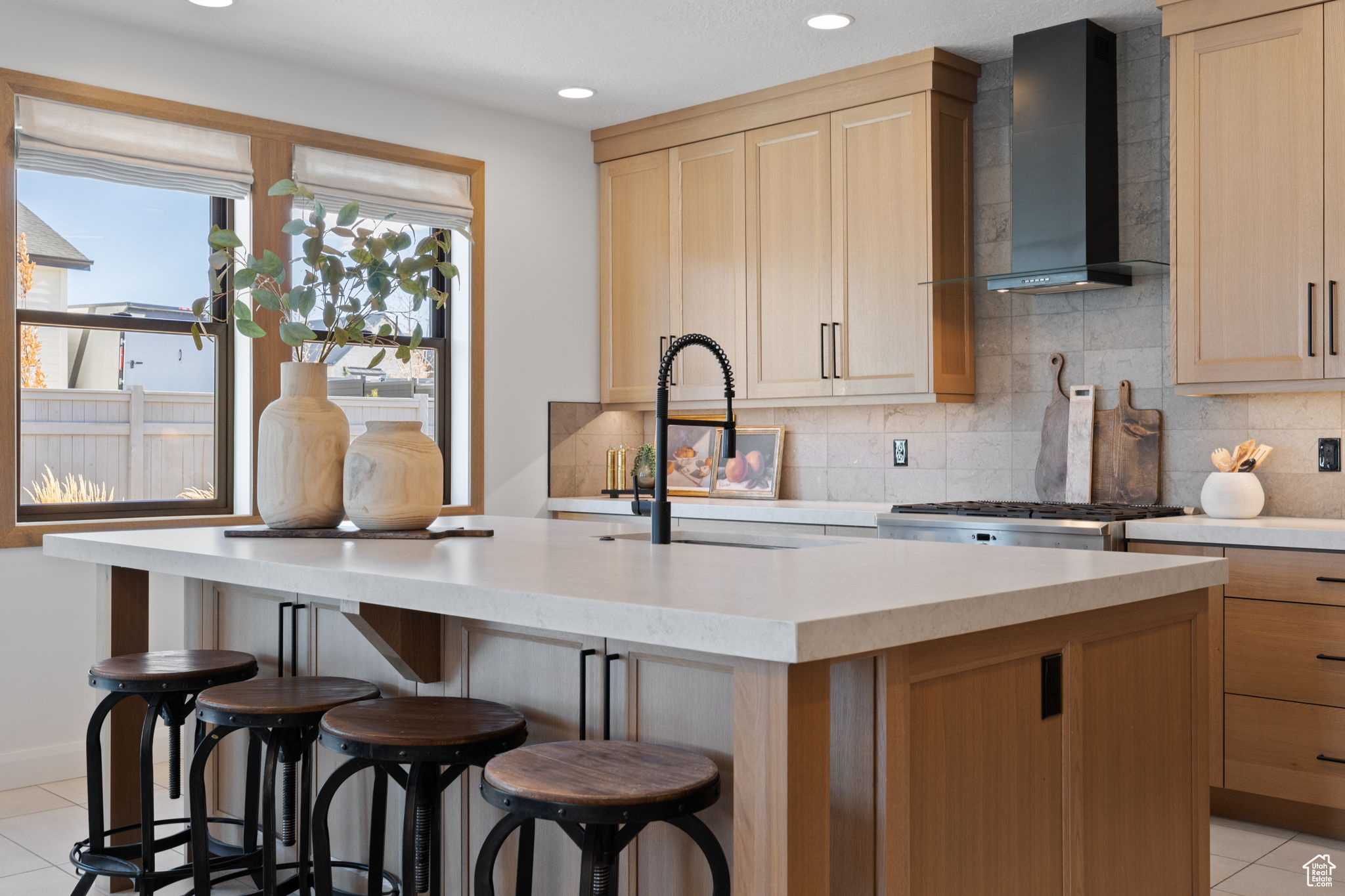 Kitchen with a kitchen bar, an island with sink, and wall chimney range hood