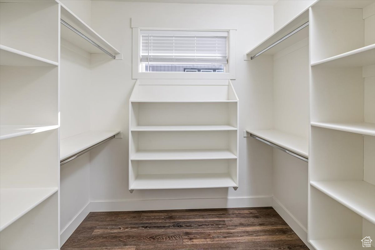 Spacious closet with dark hardwood / wood-style floors