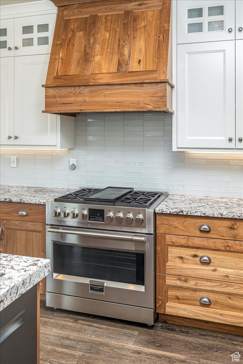 Kitchen featuring white cabinets, premium range hood, high end stainless steel range oven, and dark wood-type flooring