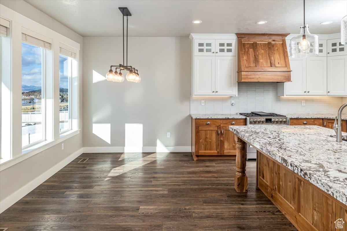 Kitchen with premium range hood, white cabinetry, high end stainless steel range, and plenty of natural light