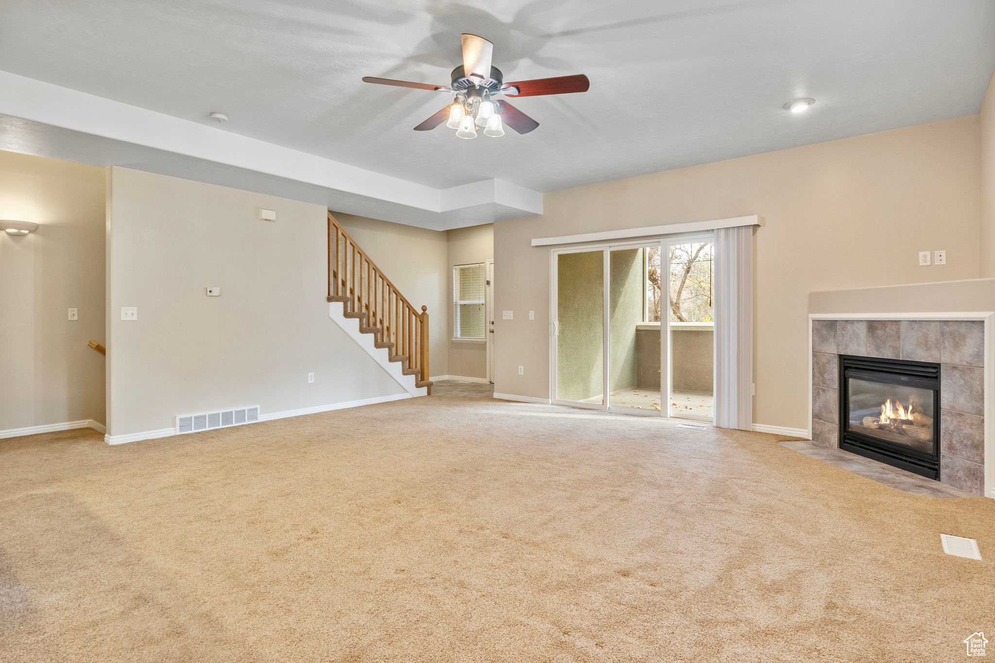 Unfurnished living room with light carpet, a fireplace, and ceiling fan