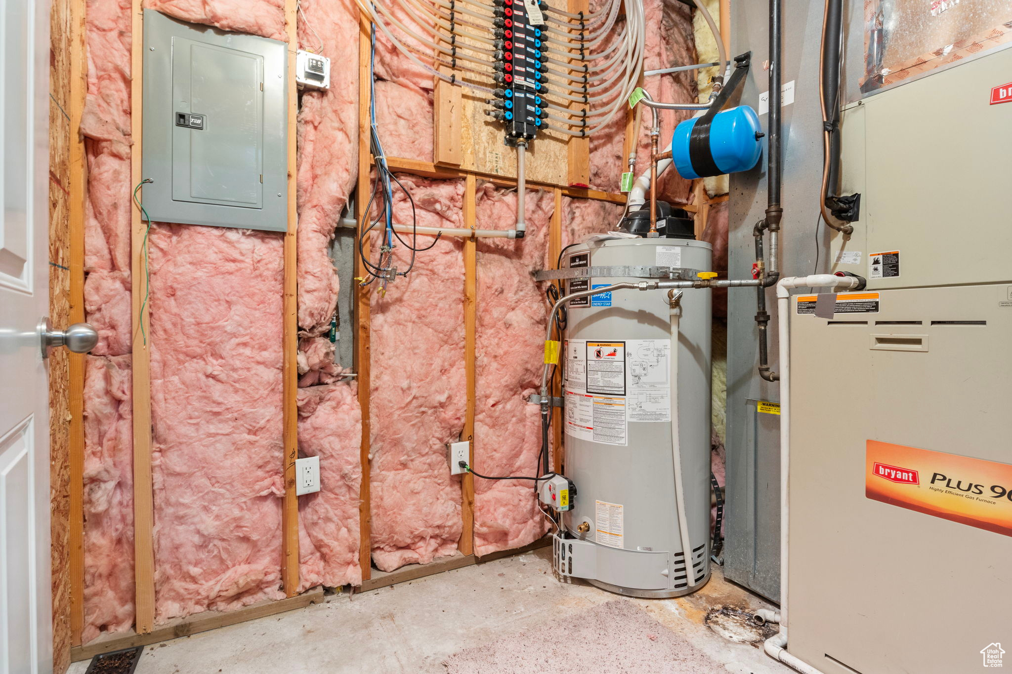 Utility room featuring heating unit, electric panel, and water heater