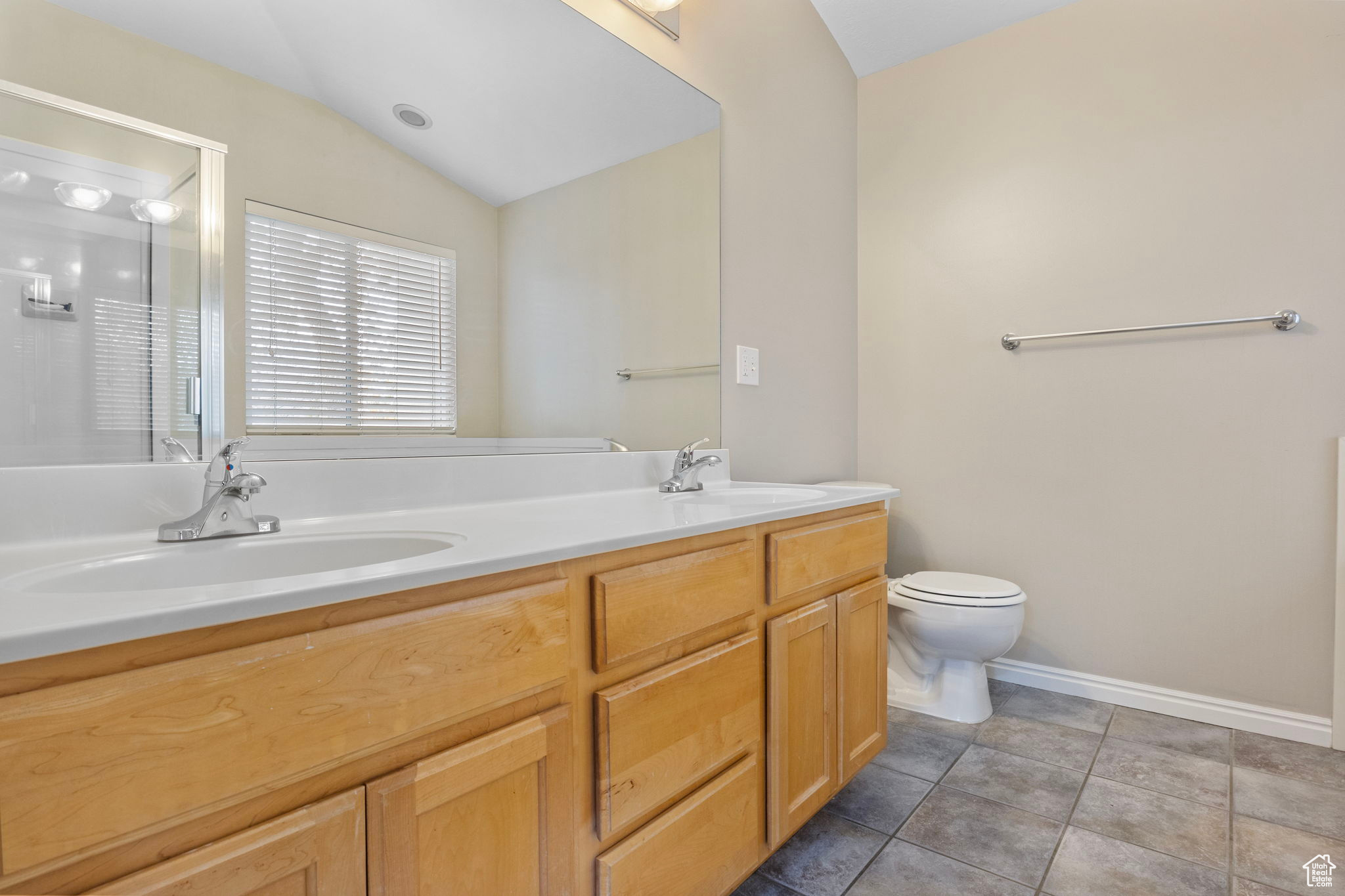 Bathroom featuring vanity, vaulted ceiling, tile patterned flooring, toilet, and a shower with shower door