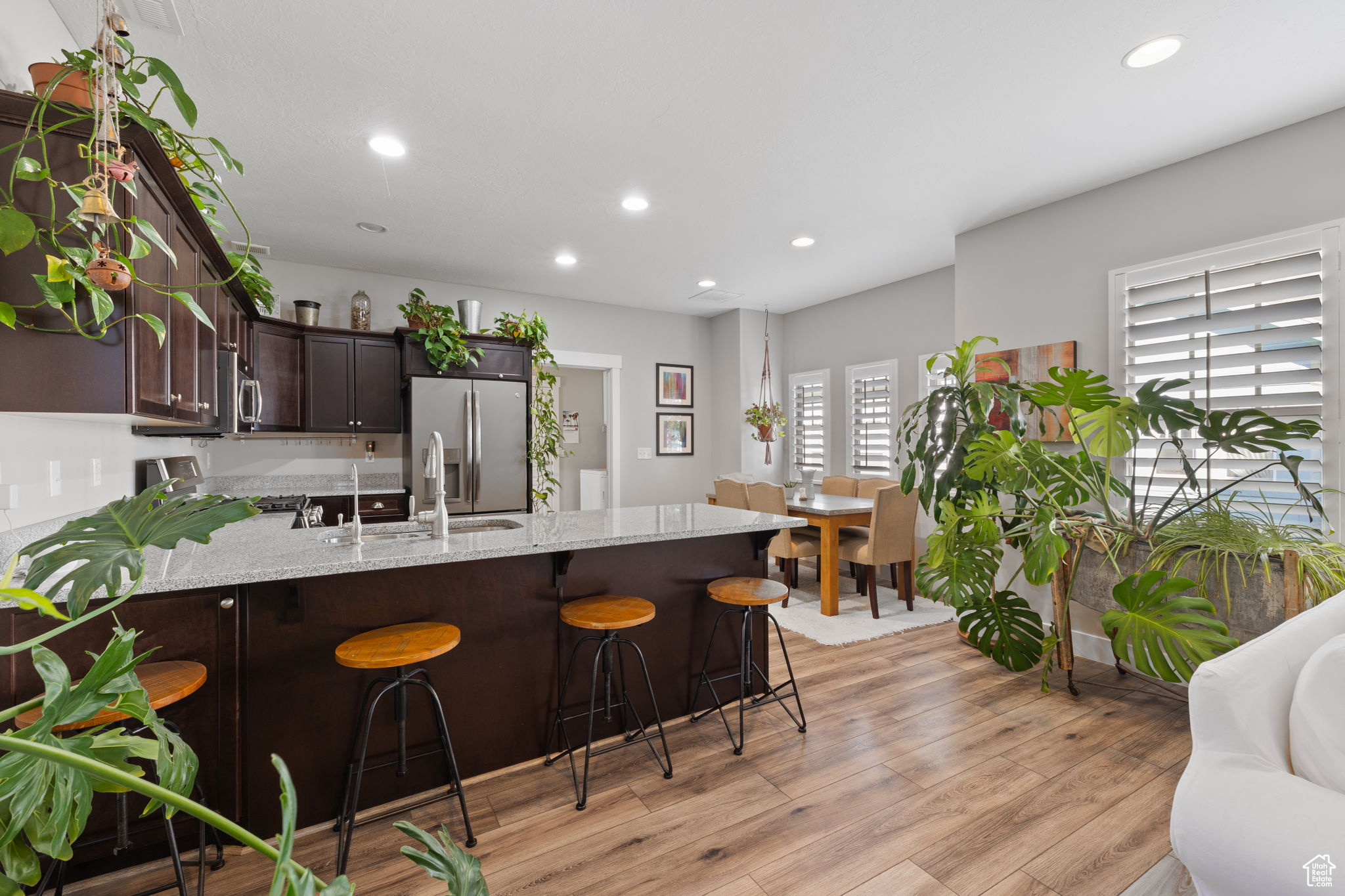 Kitchen with stainless steel refrigerator with ice dispenser, light hardwood / wood-style flooring, a breakfast bar area, and light stone counters