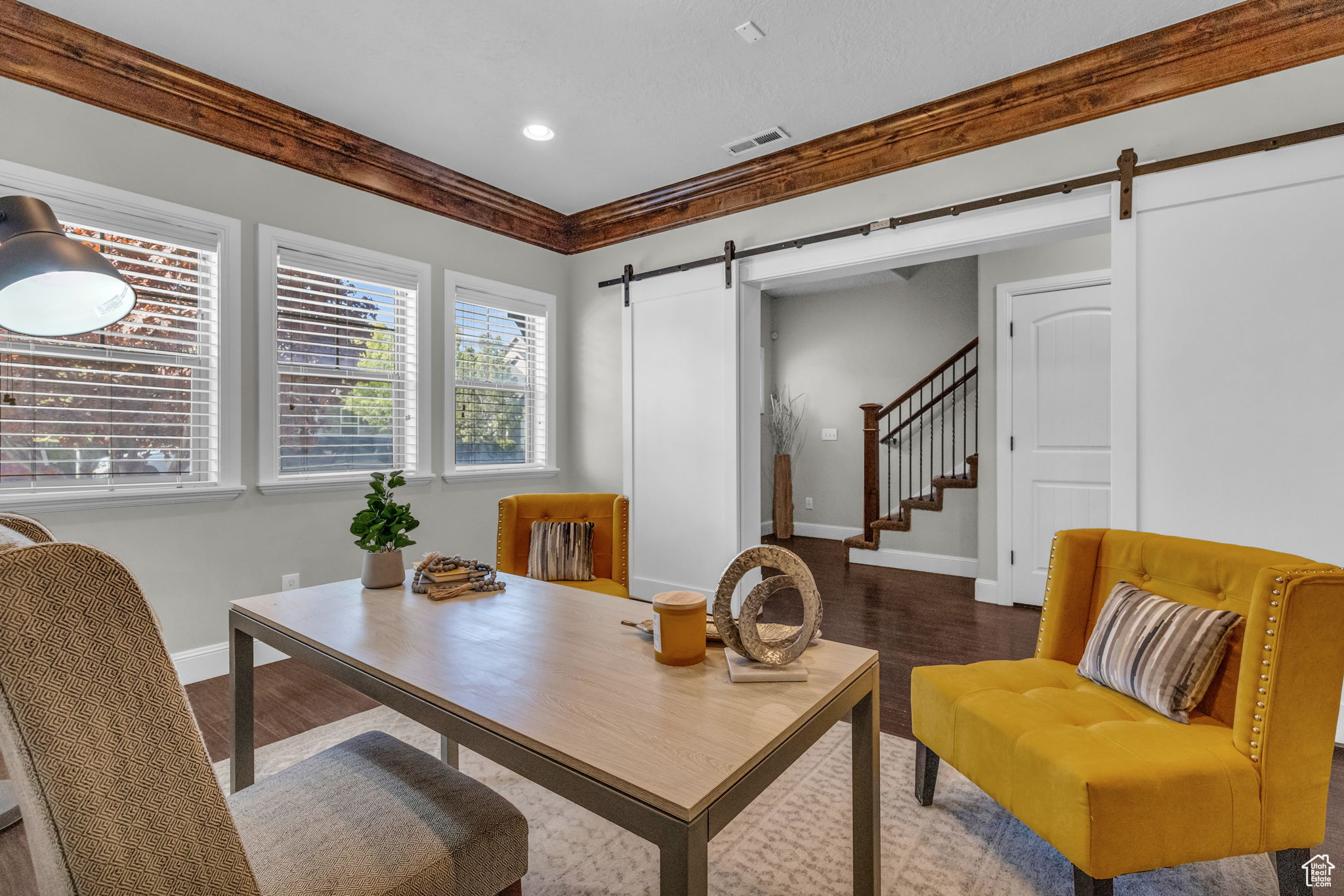 Home office featuring dark hardwood / wood-style floors, a barn door, and ornamental molding