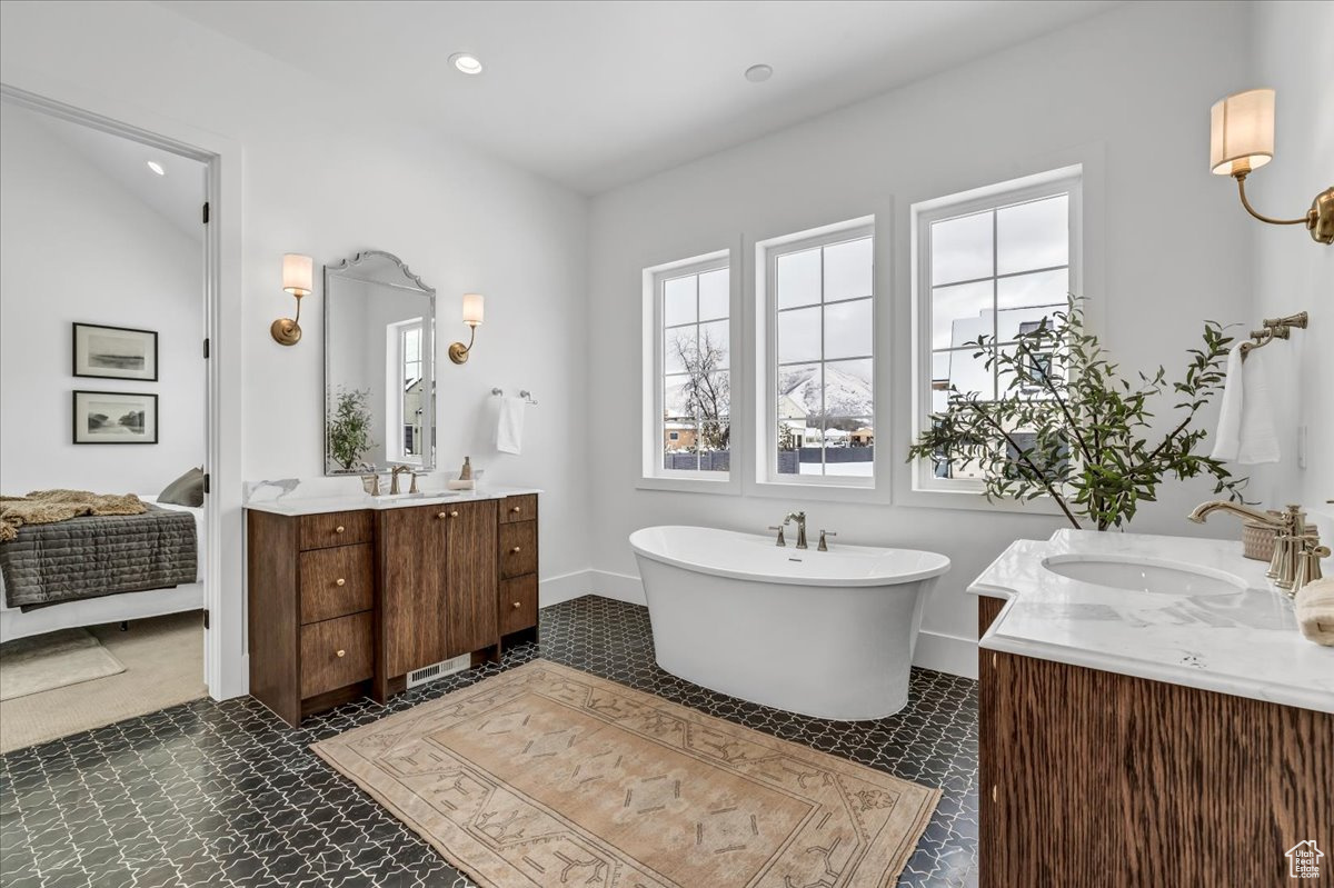 Bathroom featuring vanity, a tub, and vaulted ceiling