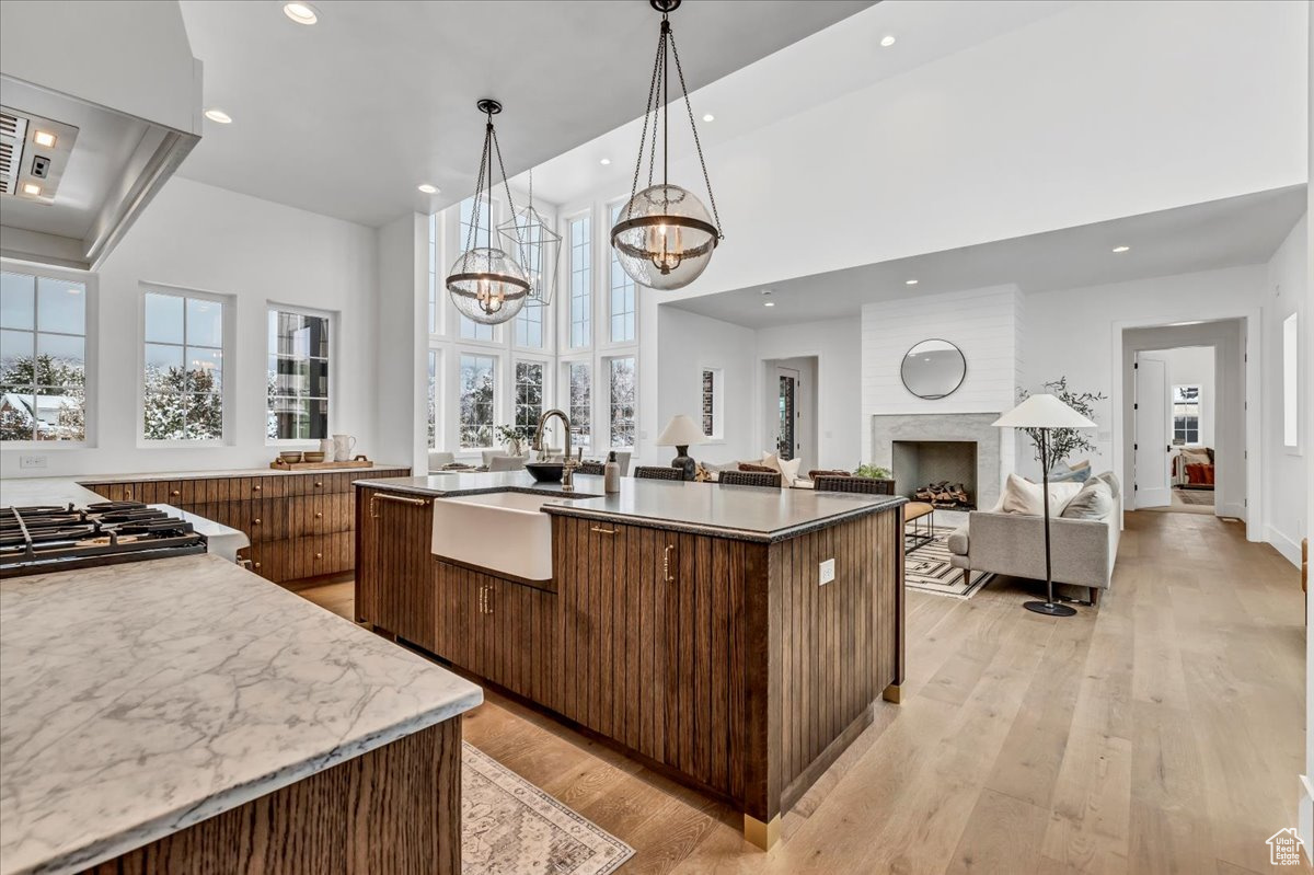 Kitchen featuring extractor fan, sink, a large island with sink, light hardwood / wood-style flooring, and a notable chandelier