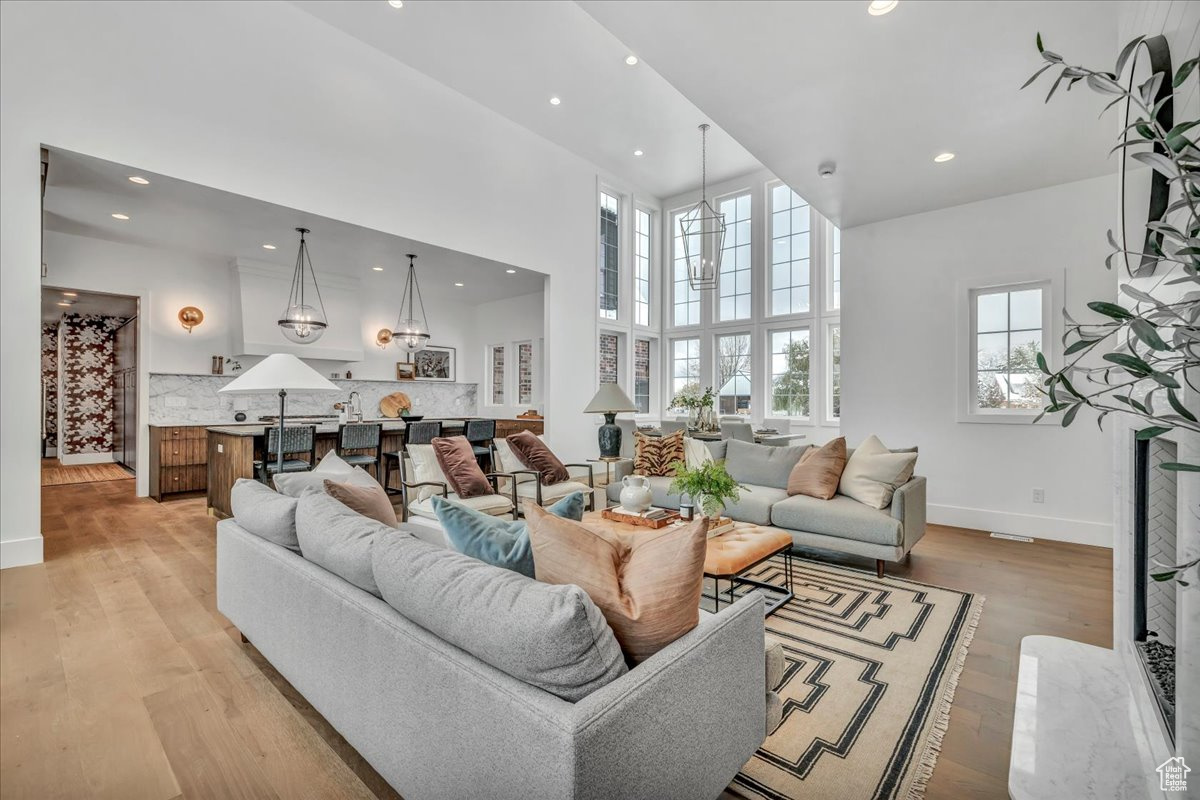 Living room with a high ceiling, light hardwood / wood-style flooring, and a wealth of natural light