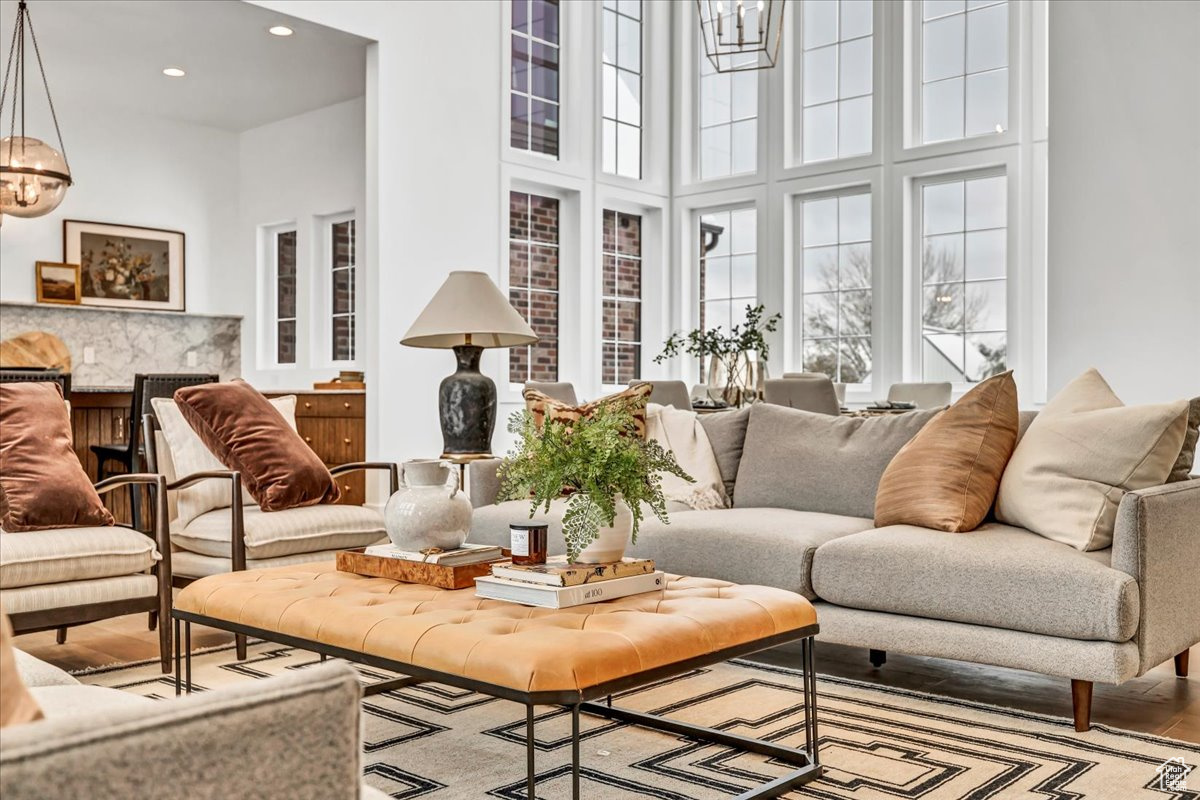 Living room with light hardwood / wood-style flooring, a towering ceiling, and an inviting chandelier