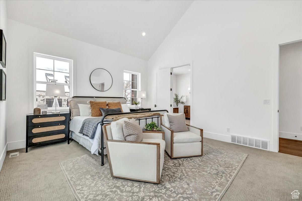 Bedroom featuring light colored carpet and high vaulted ceiling