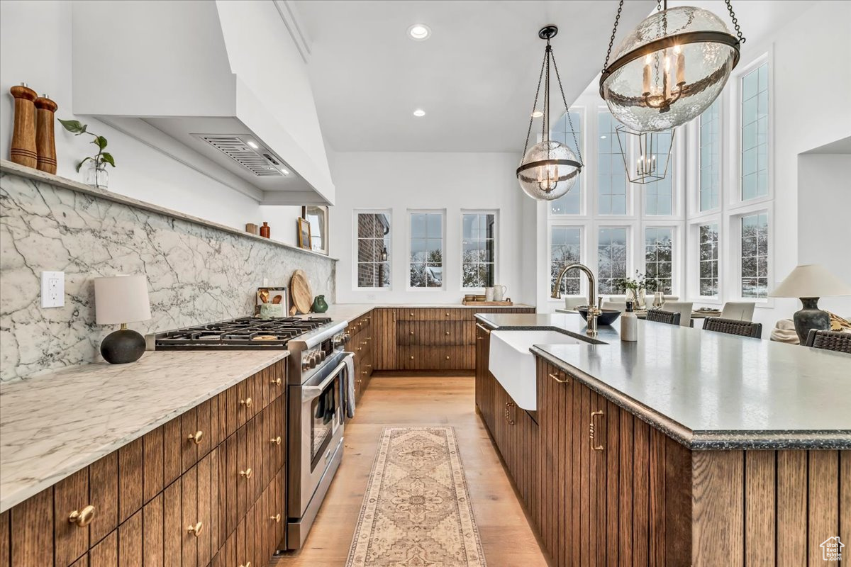 Kitchen featuring pendant lighting, sink, high end stainless steel range oven, light wood-type flooring, and a chandelier