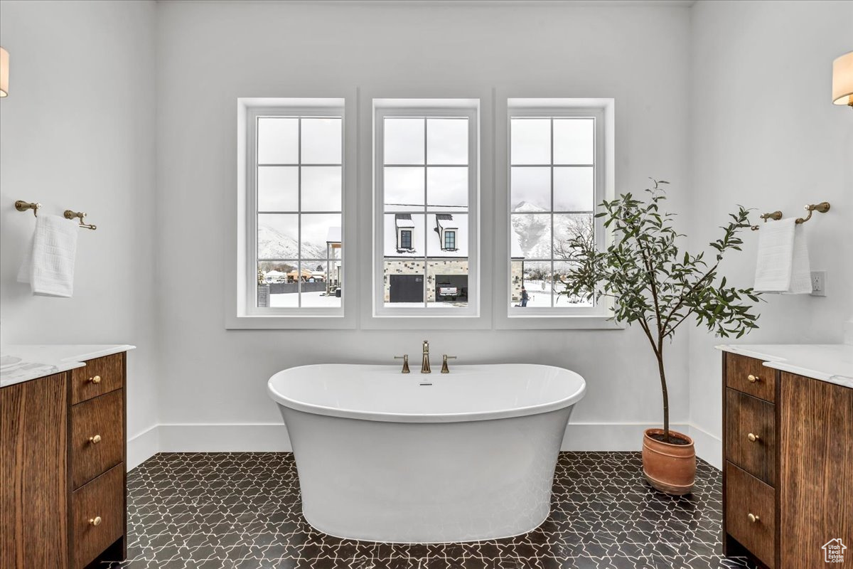 Bathroom with vanity, a wealth of natural light, and a tub