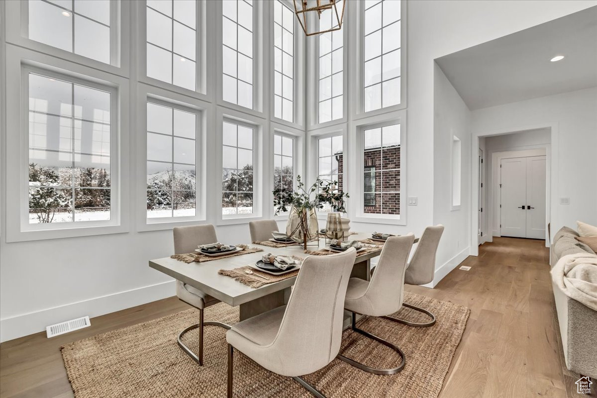 Dining room with light hardwood / wood-style floors and a towering ceiling