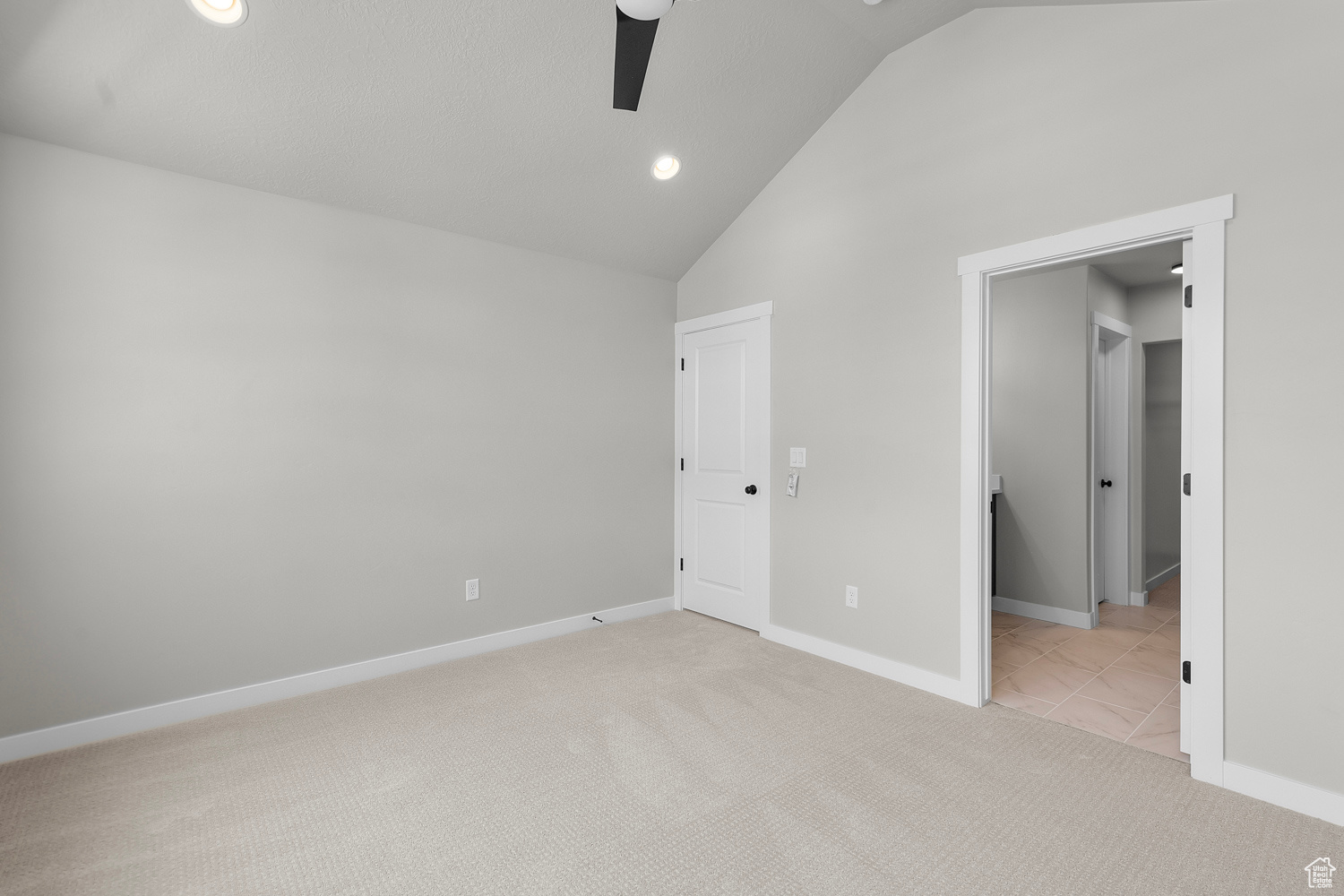 Unfurnished bedroom featuring ceiling fan, light colored carpet, and high vaulted ceiling