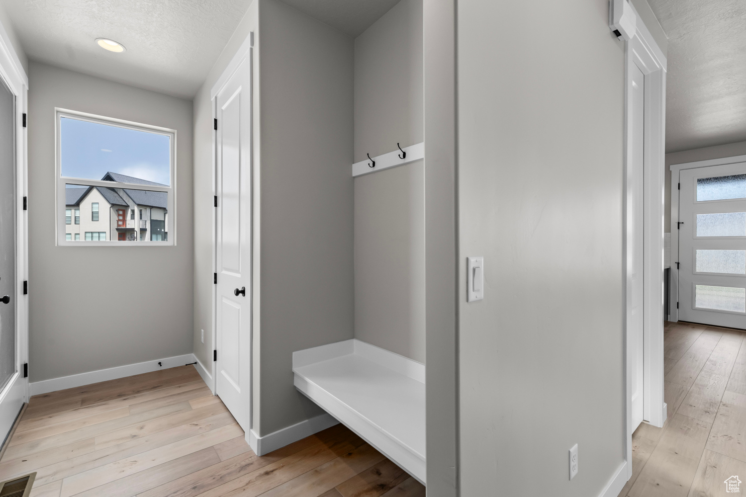 Mudroom with light wood-type flooring and a textured ceiling