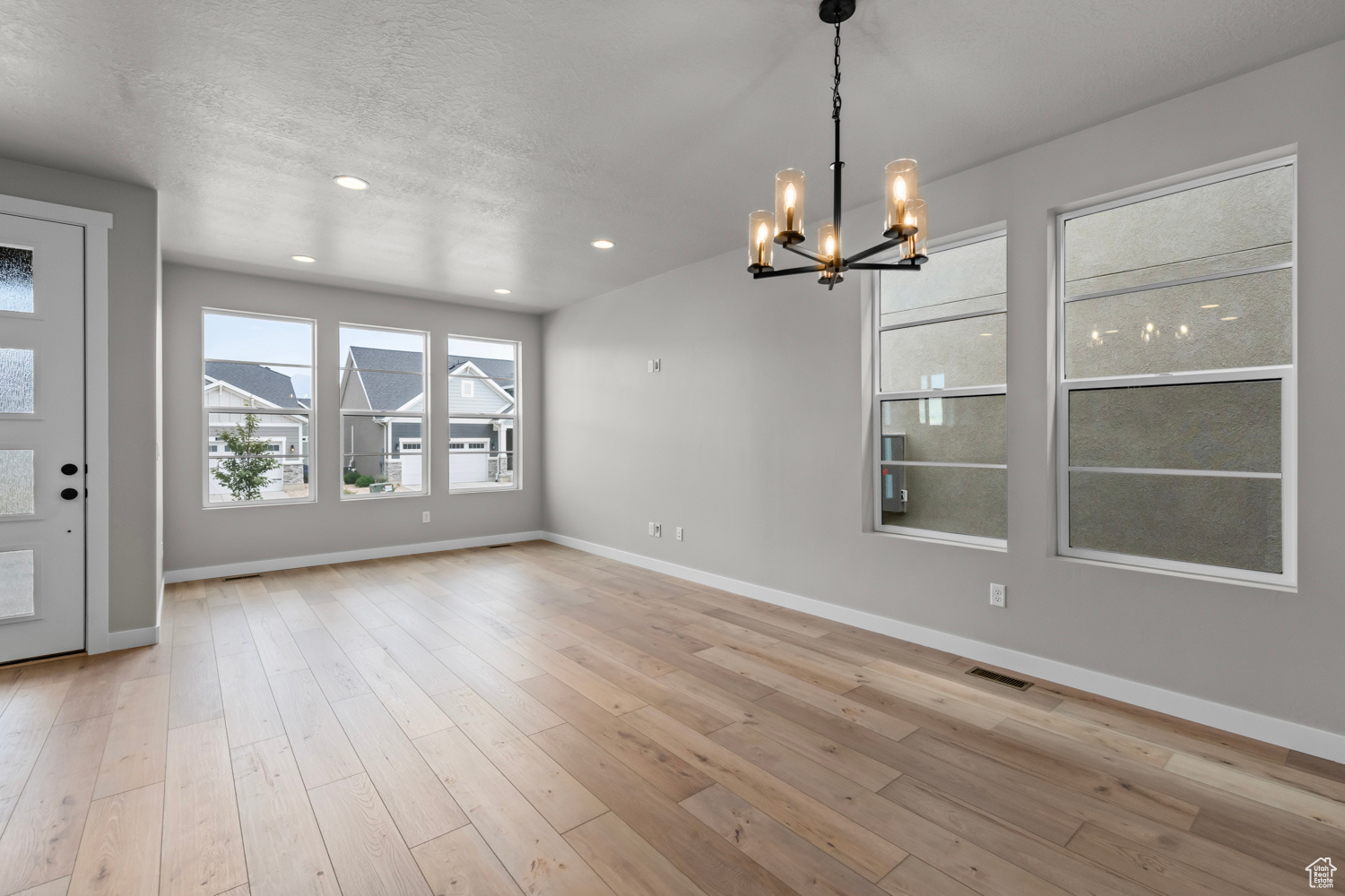 Interior space with a chandelier, a textured ceiling, and light wood-type flooring