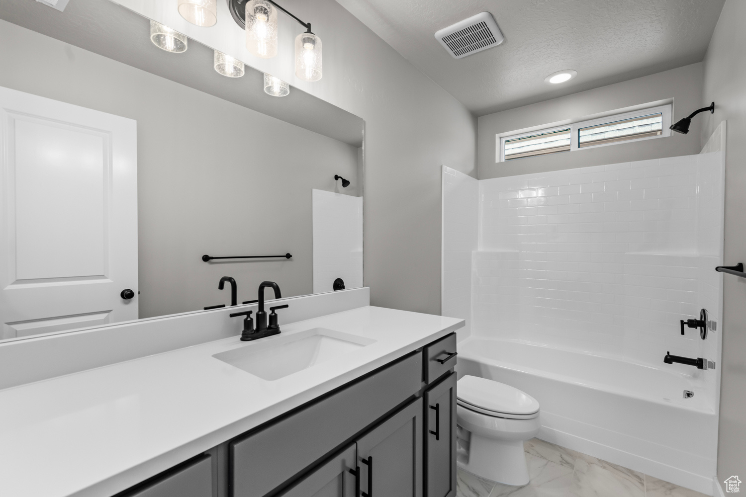 Full bathroom featuring a textured ceiling, vanity, toilet, and shower / bathtub combination