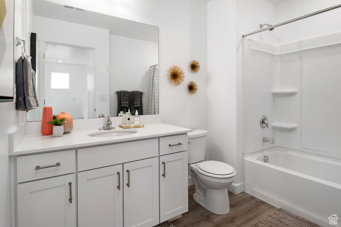 Full bathroom with vanity,  shower combination, hardwood / wood-style flooring, and toilet