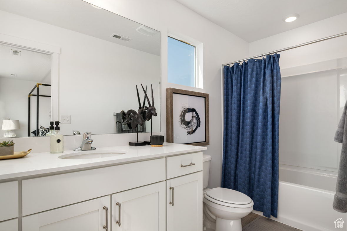 Full bathroom featuring shower / tub combo with curtain, vanity, and toilet