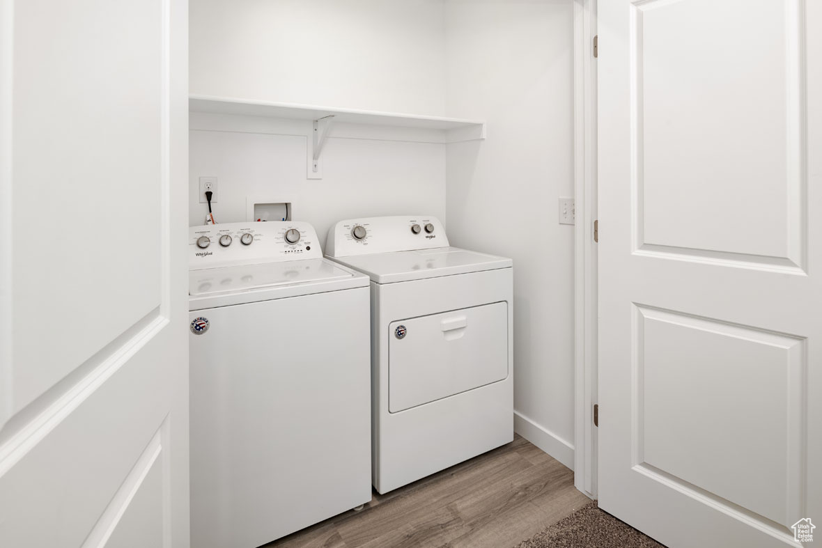 Clothes washing area featuring light wood-type flooring and separate washer and dryer