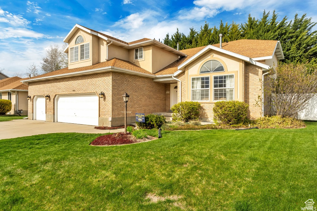 View of front of house featuring a front lawn and a garage